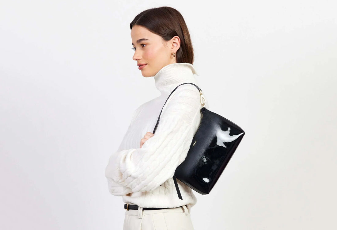 Woman holding a black handbag on a plain background