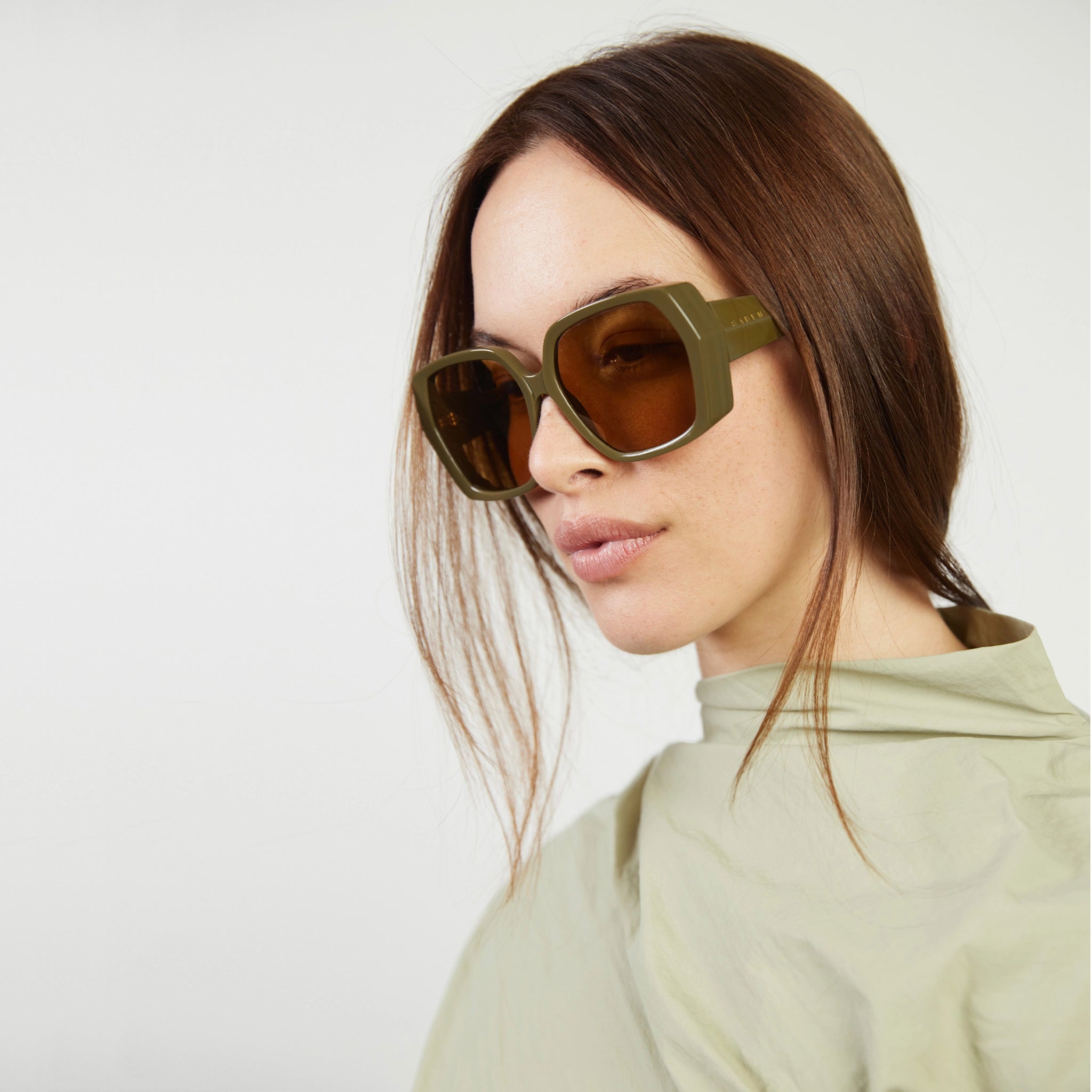 Woman wearing large sunglasses with a neutral background