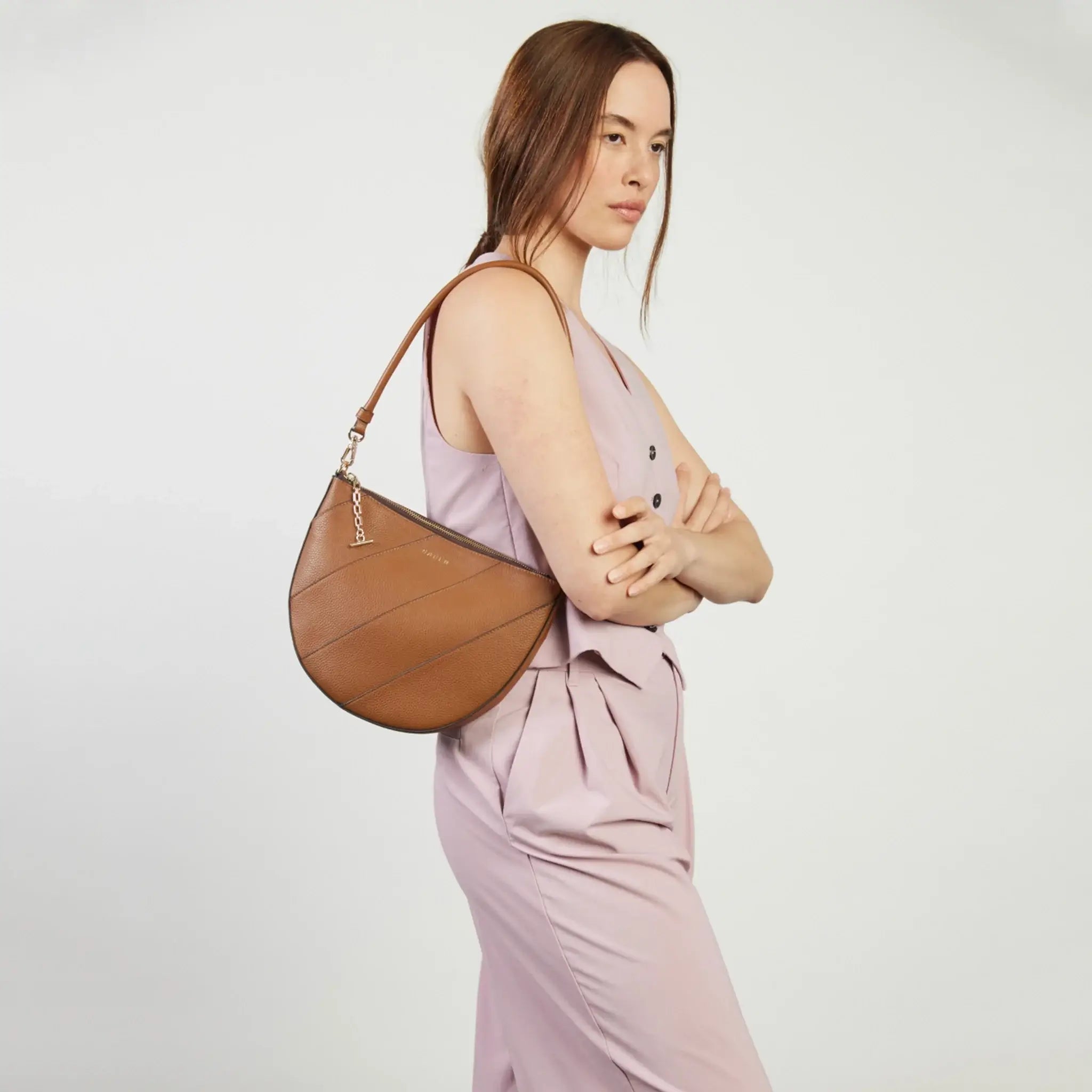 Woman holding a brown handbag against a white background