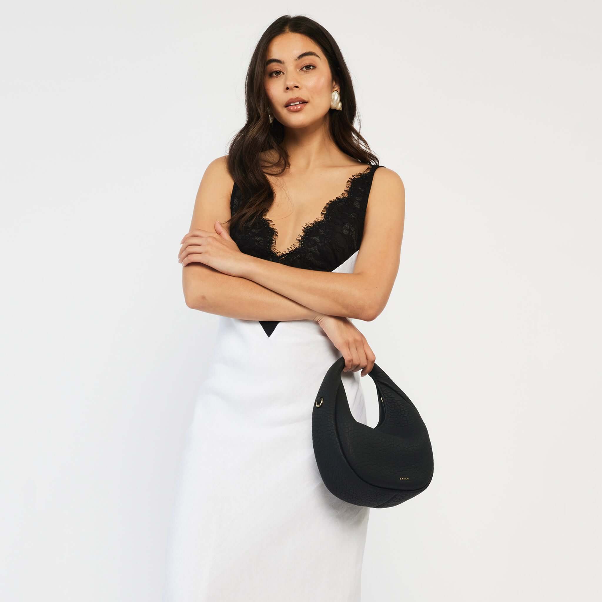 Saben Halle Mini Bag - Black Bubble black textured leather circular mini bag with detachable crossbody strap, model holding
