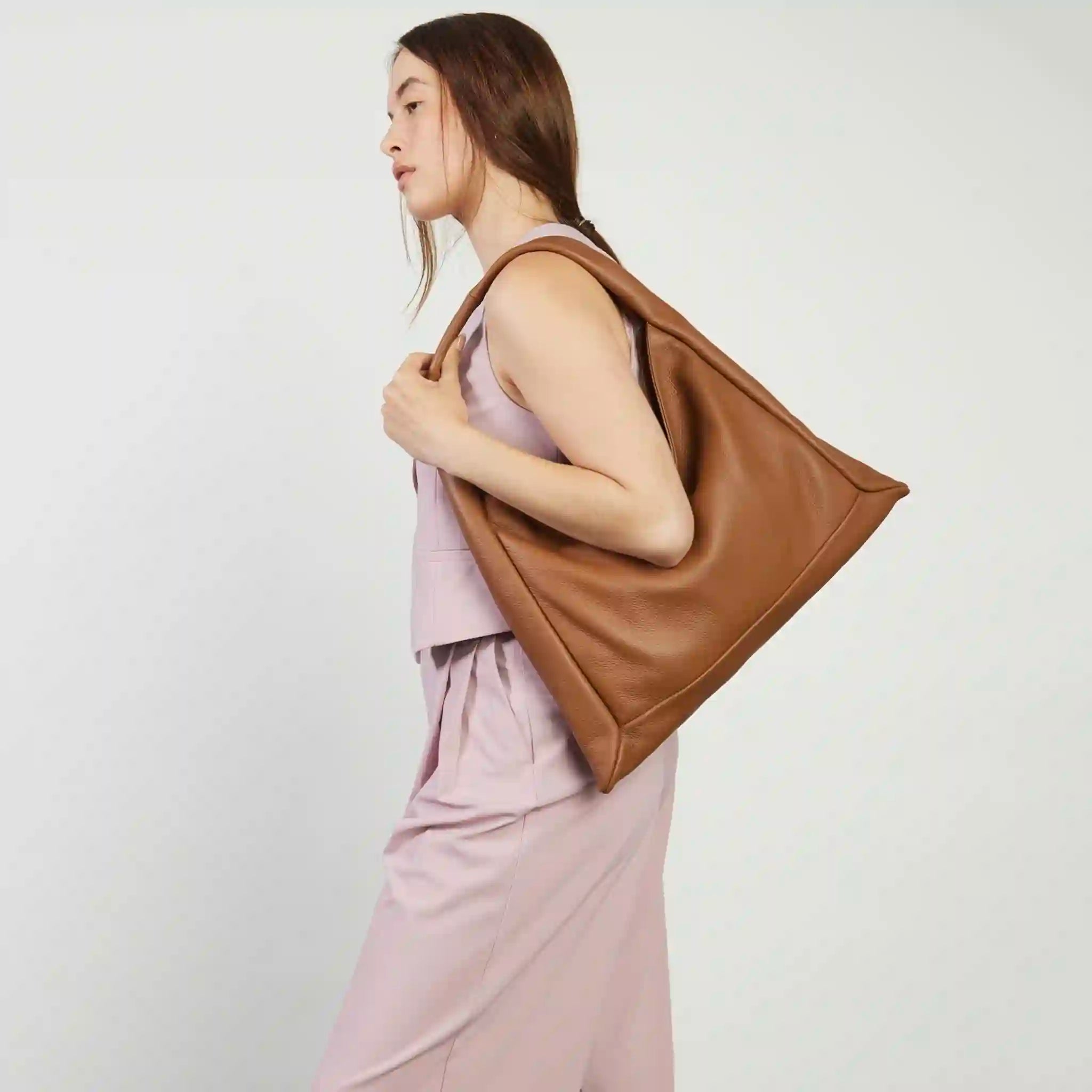 Woman holding a brown leather bag against a white background