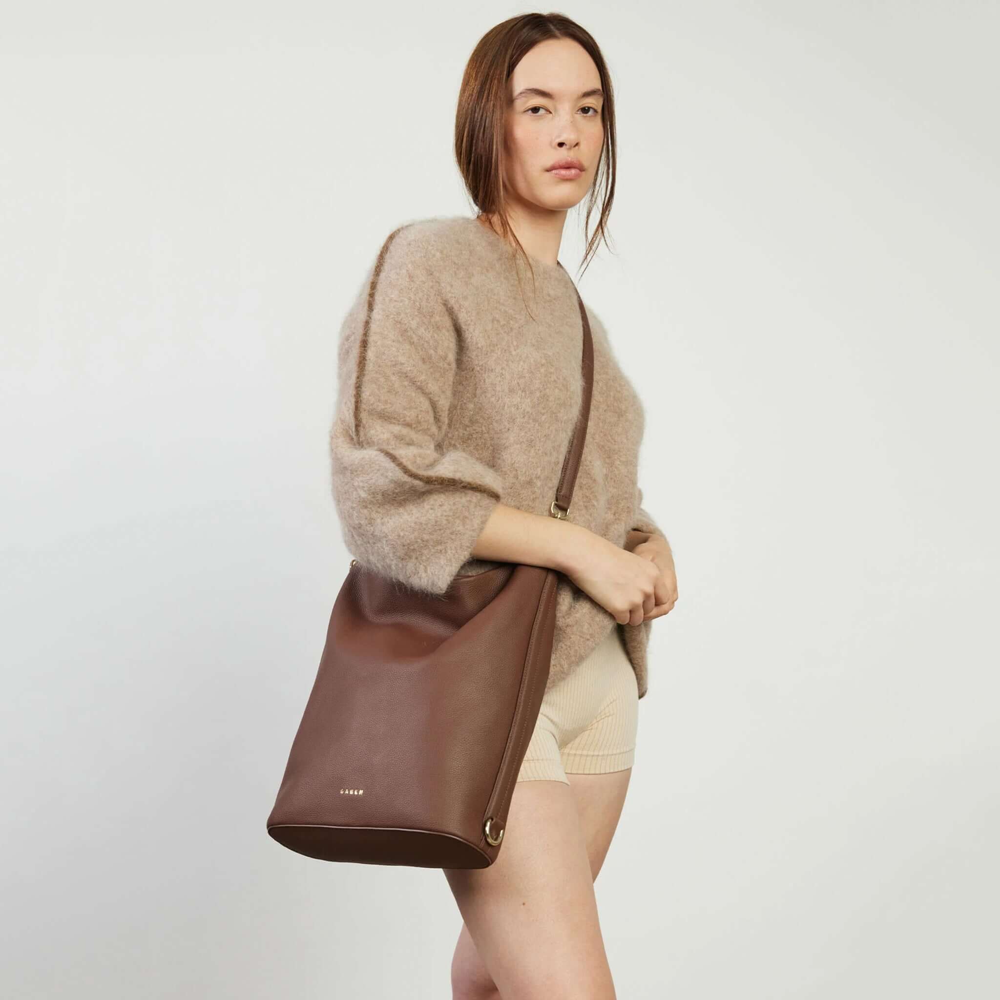 Alt Tag: Saben June Shoulder Bag - Umber bucket-style tote with adjustable shoulder strap, shown worn crossbody by model