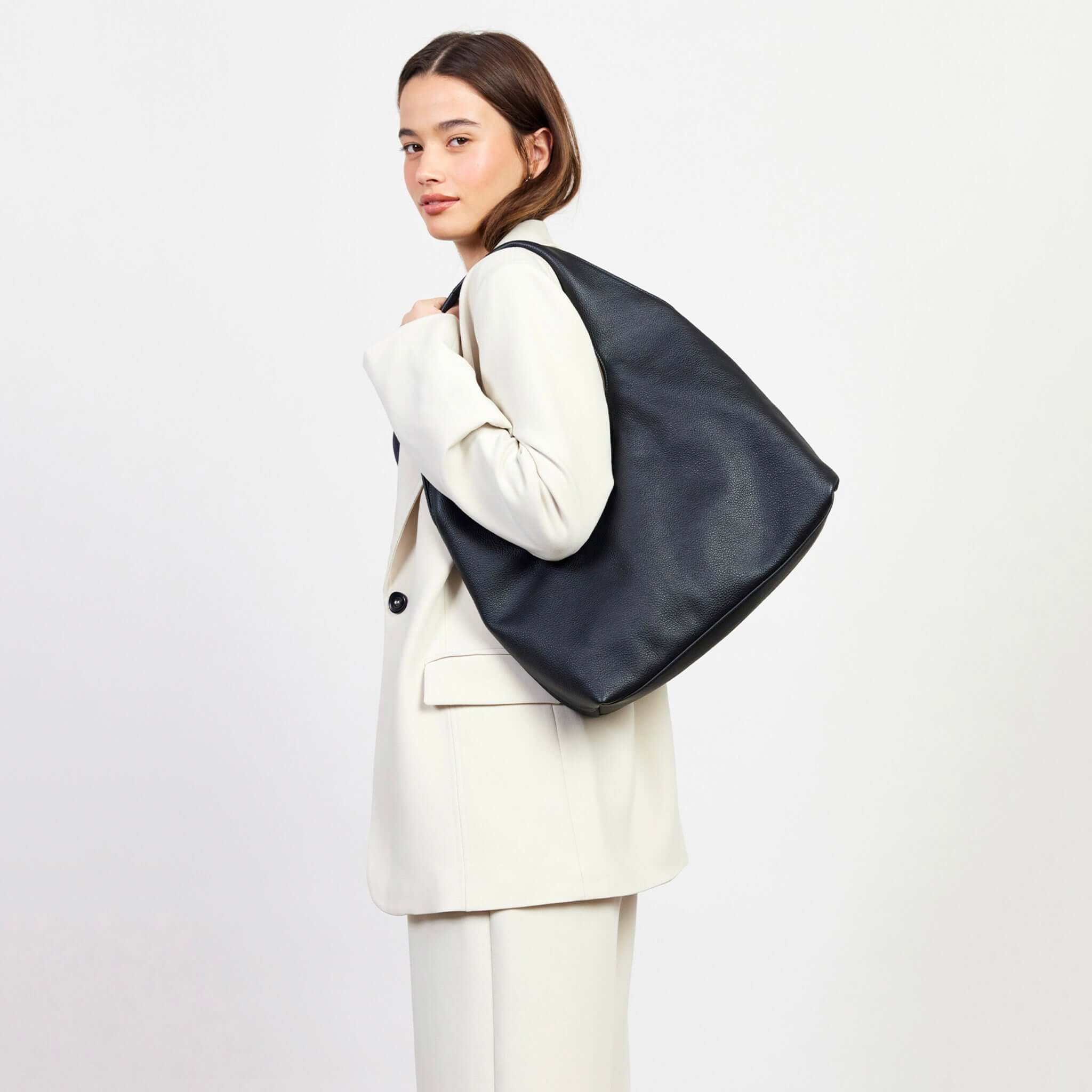 Alt Tag: Saben Kip Shoulder Bag - Lightly Milled Black slouchy black shoulder bag worn by model, roomy chic everyday carryall