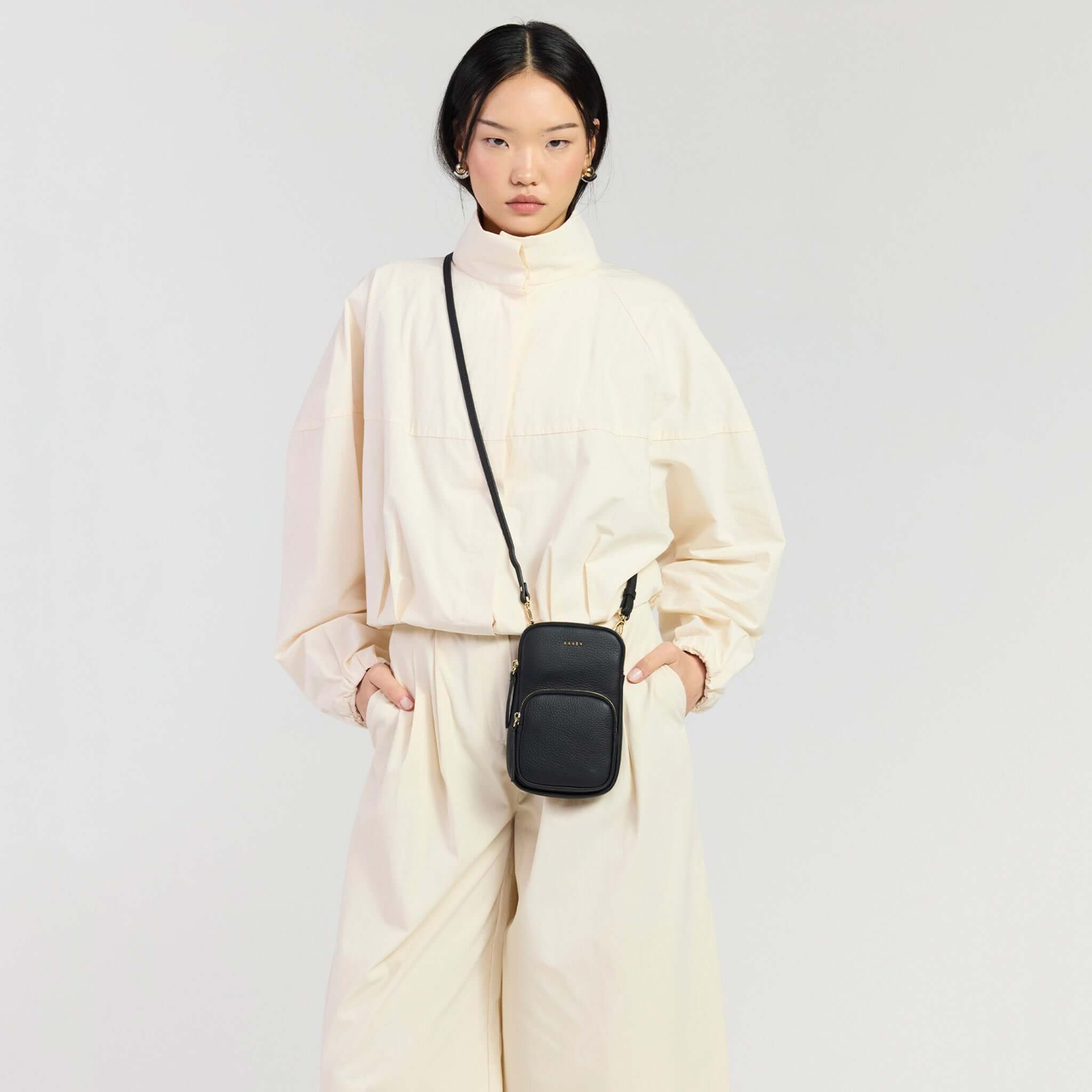 Model wearing Saben Nikko Pocket Phone Sling - Black Luxe, styled in a modern outfit.