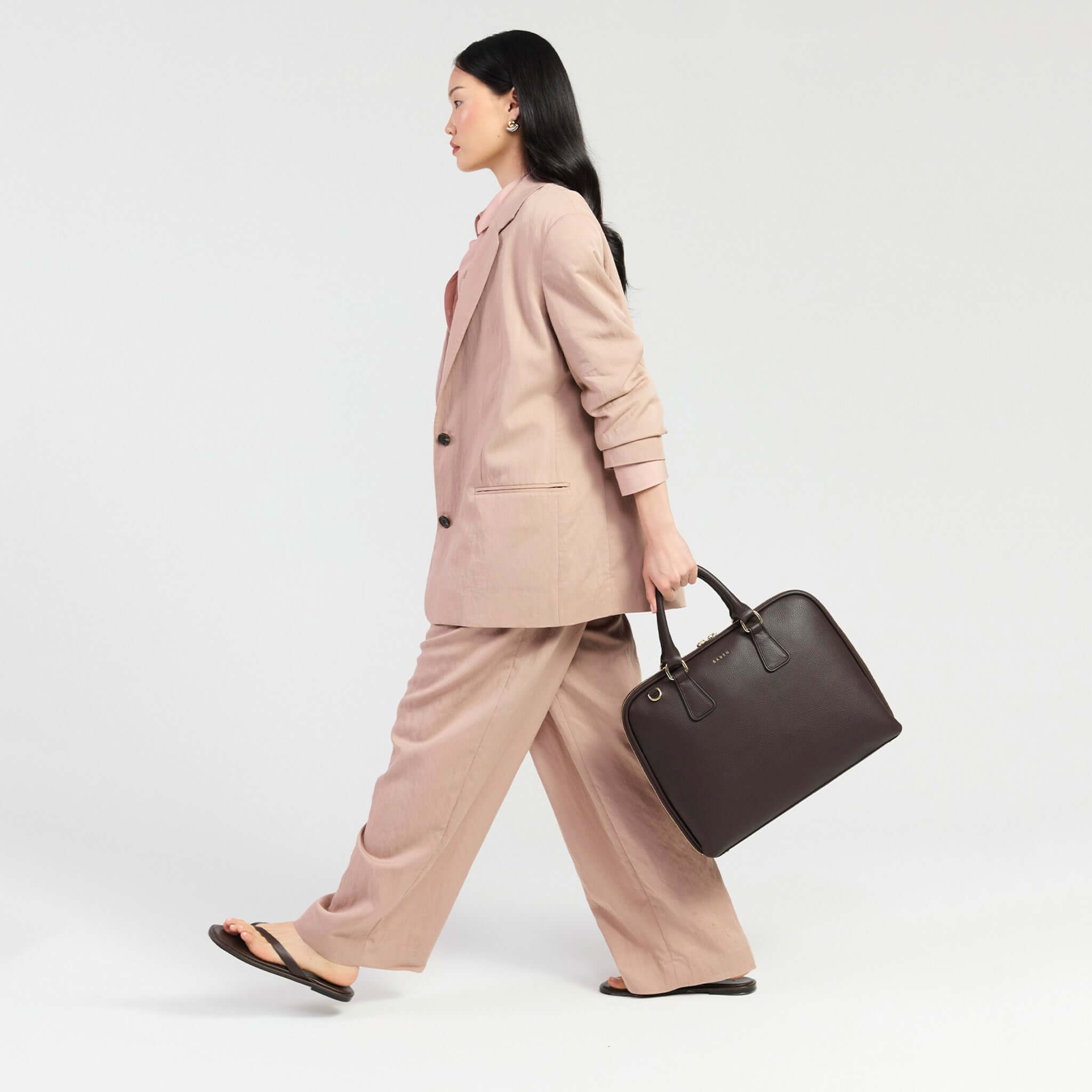 Woman in a pink suit carrying a Saben Parker Briefcase - Cacao, showcasing style and professionalism.