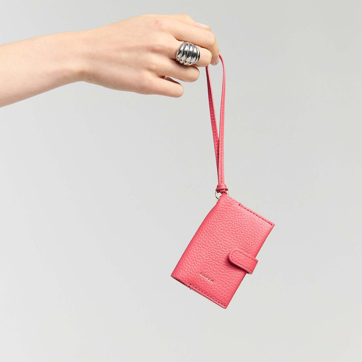 Saben Sid Card Holder - Azalea in hand, showcasing compact design and detachable wristlet strap.