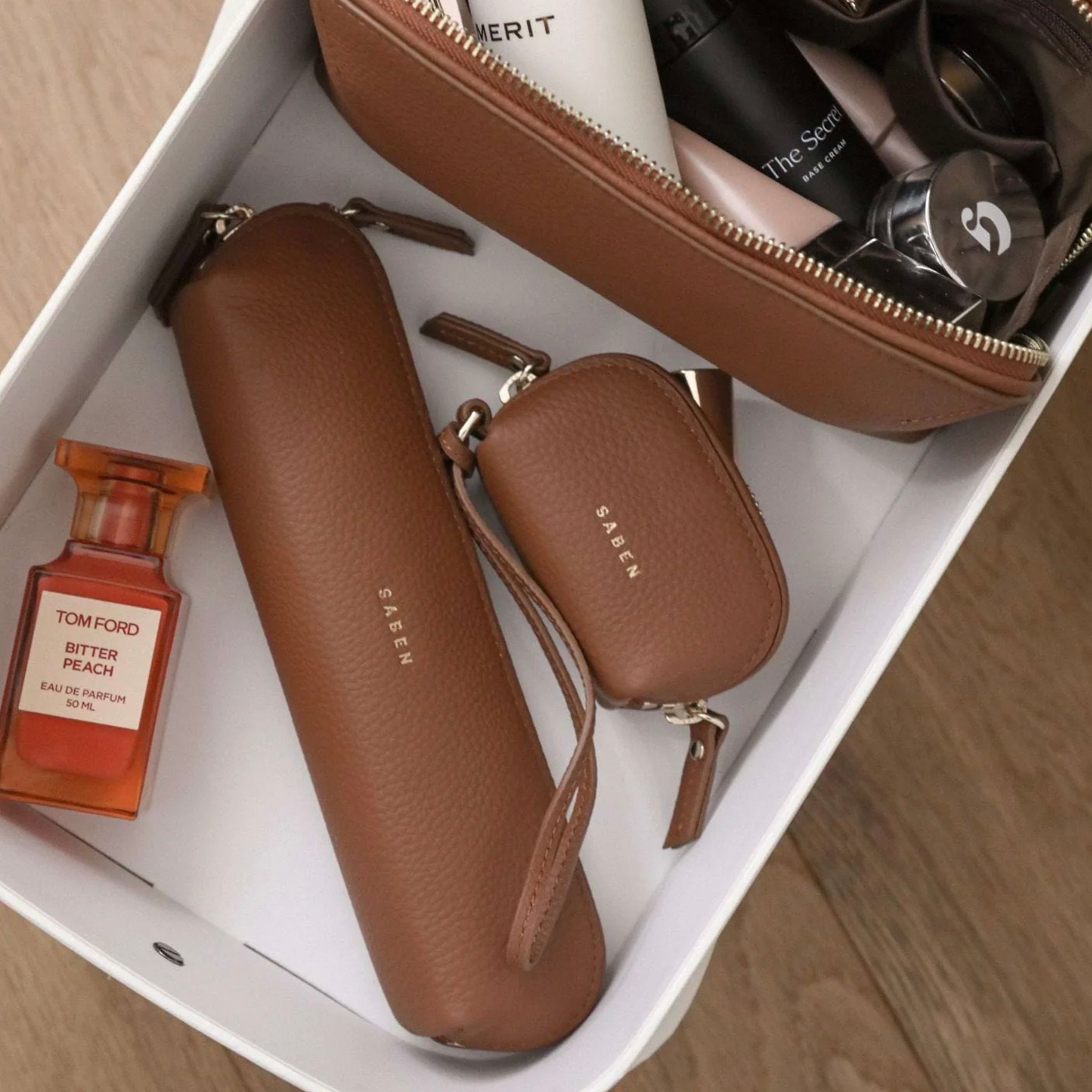 Brown leather products including a pouch, case, and small wallet on a white surface.