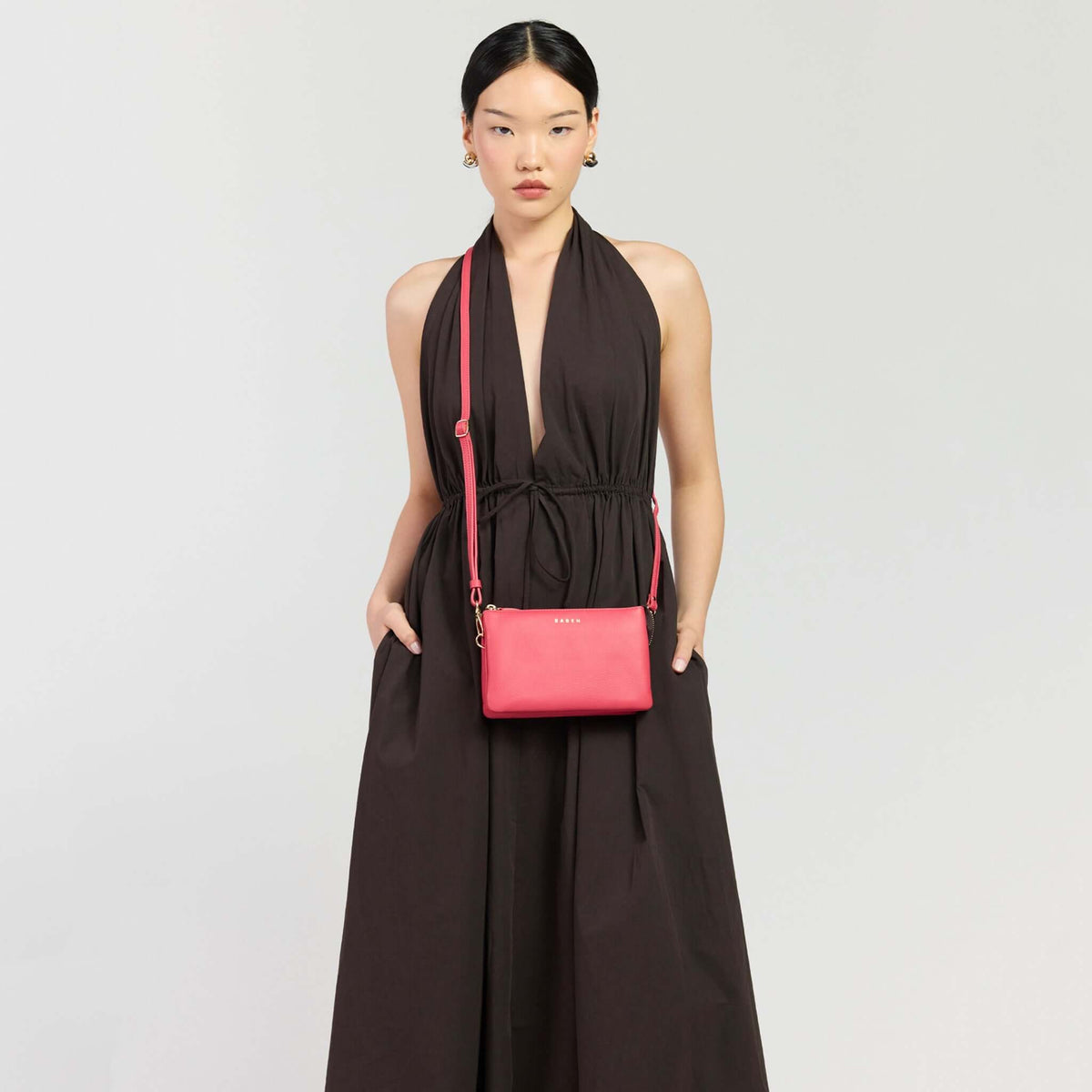 Saben Tilly Crossbody Bag - Azalea worn by a model with a stylish black dress.