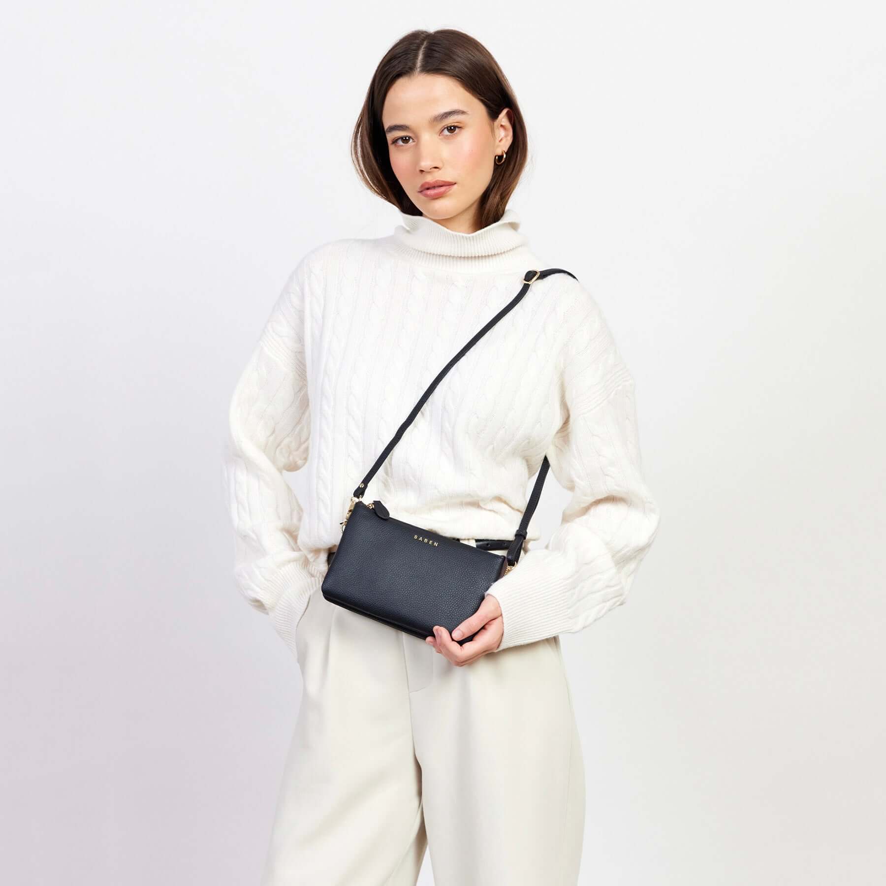 Alt Tag: Saben Tilly Crossbody Bag - Black worn as a black leather crossbody bag with adjustable strap, compact wallet-clutch design