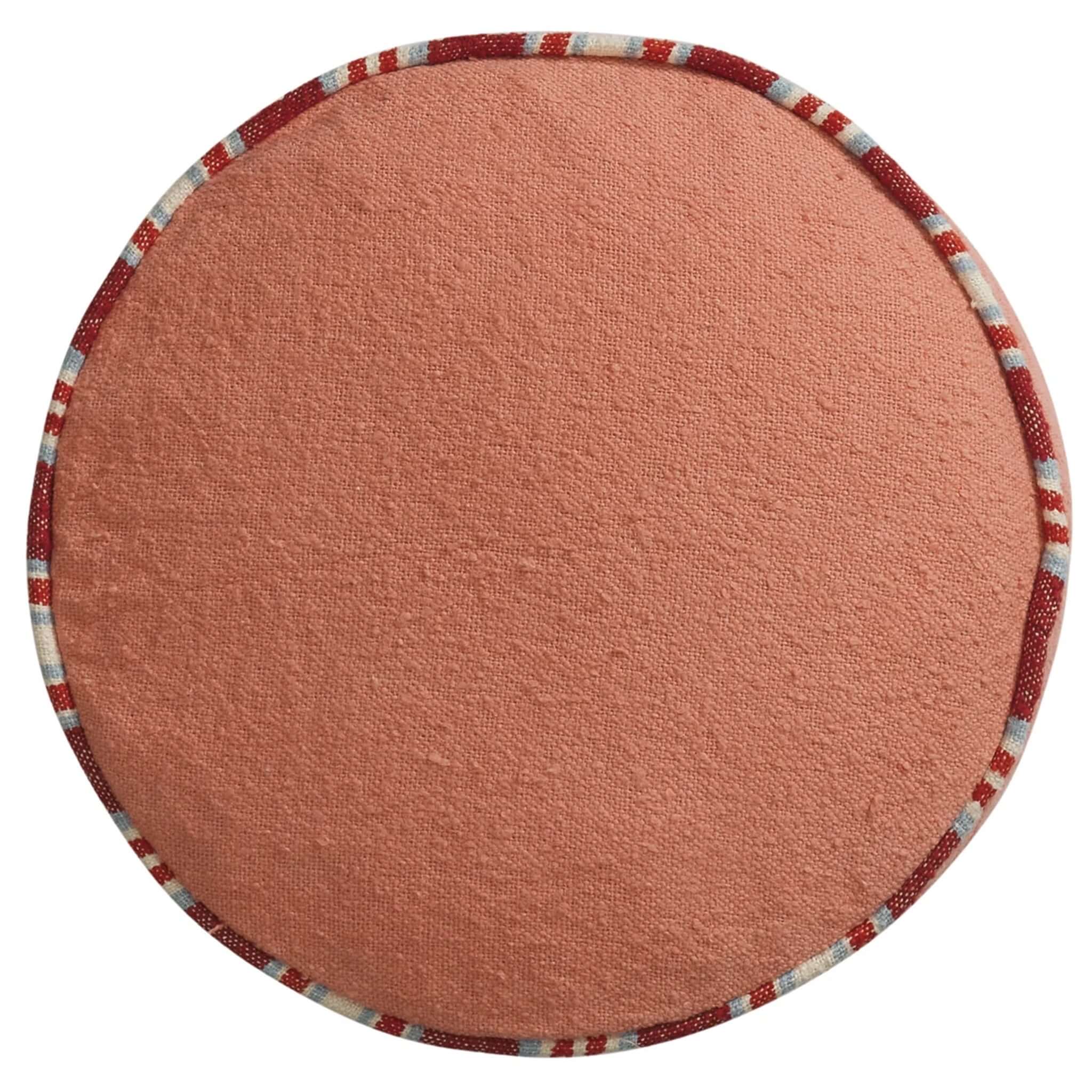 Round pink fabric cushion with a colorful border on a white background