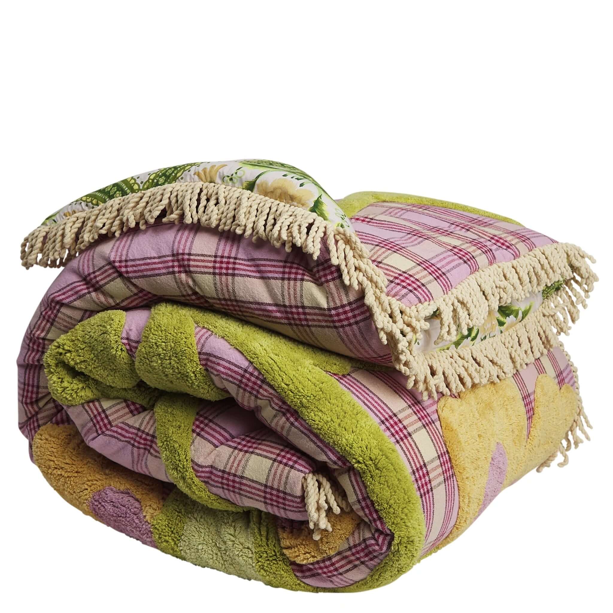 Folded patchwork blanket with fringes on a white background