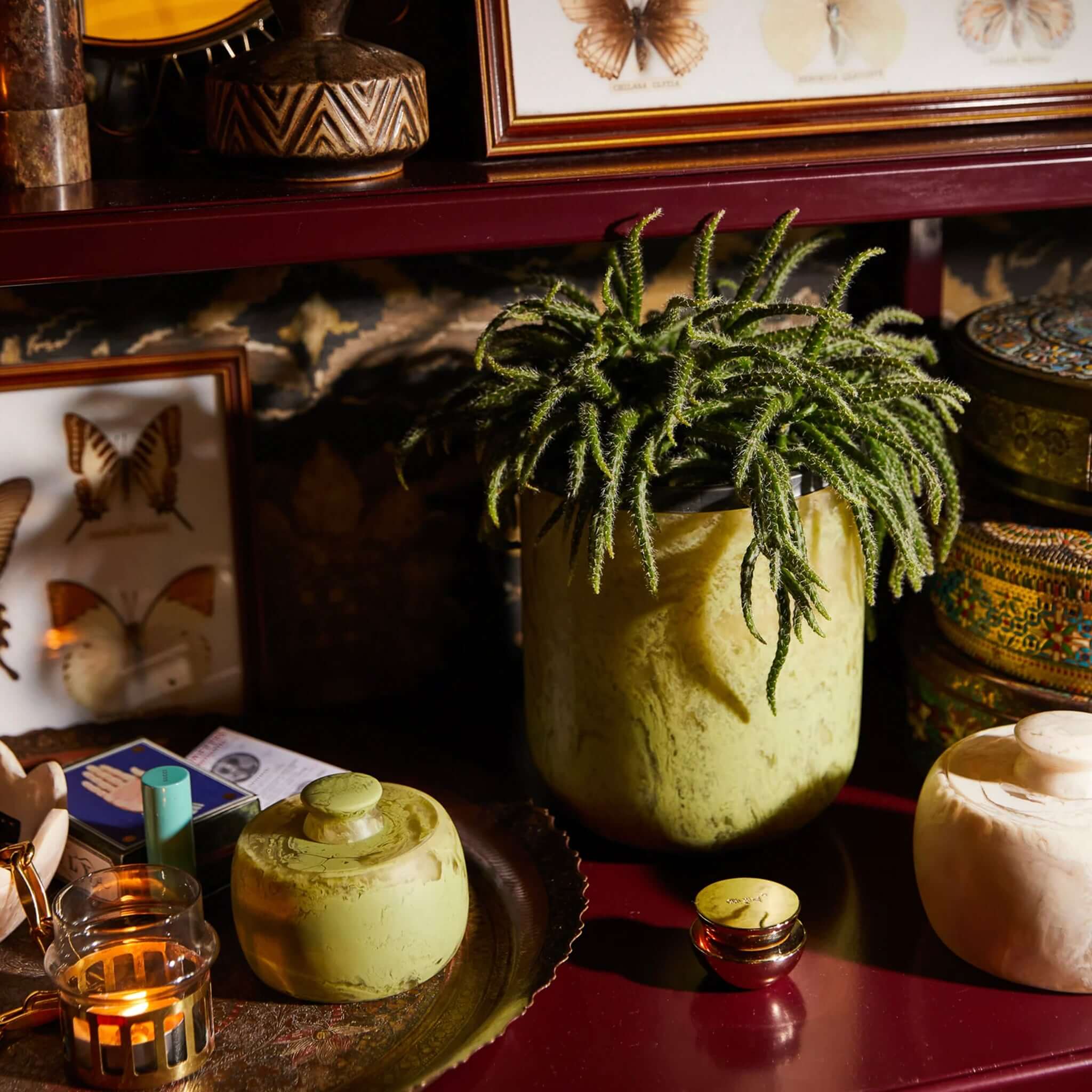 A hand-poured pistachio green resin vase with a mid-century inspired design on a shelf.