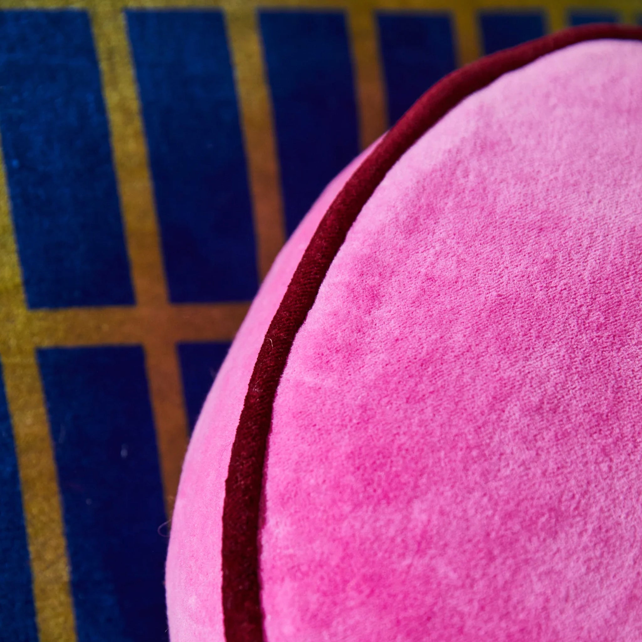 Close-up of a pink cushion with a textured surface on a blue and yellow checkered background