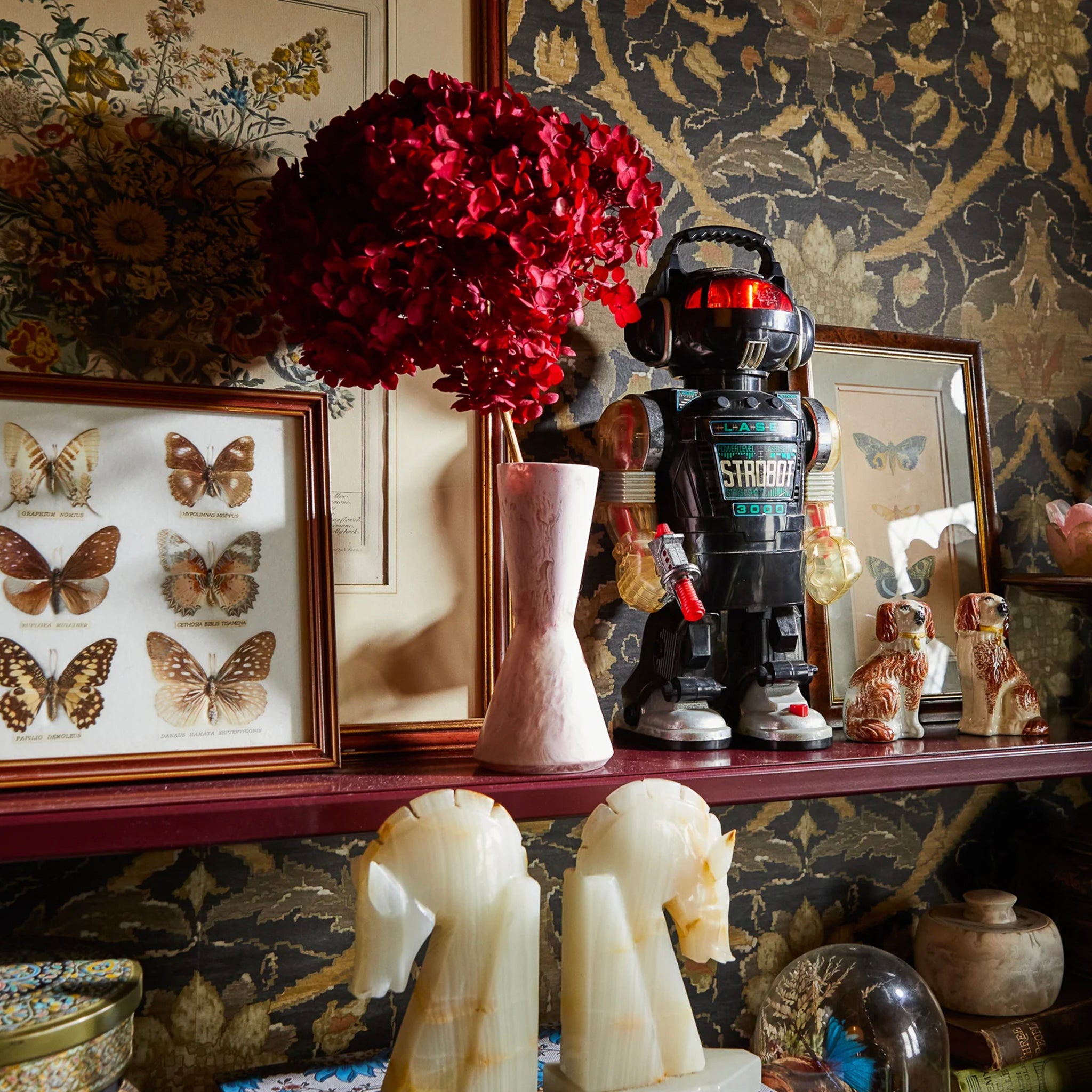 A conical resin vase with a pink hue, featuring a narrower top and bottom with a wider middle section, intended for holding small floral arrangements.