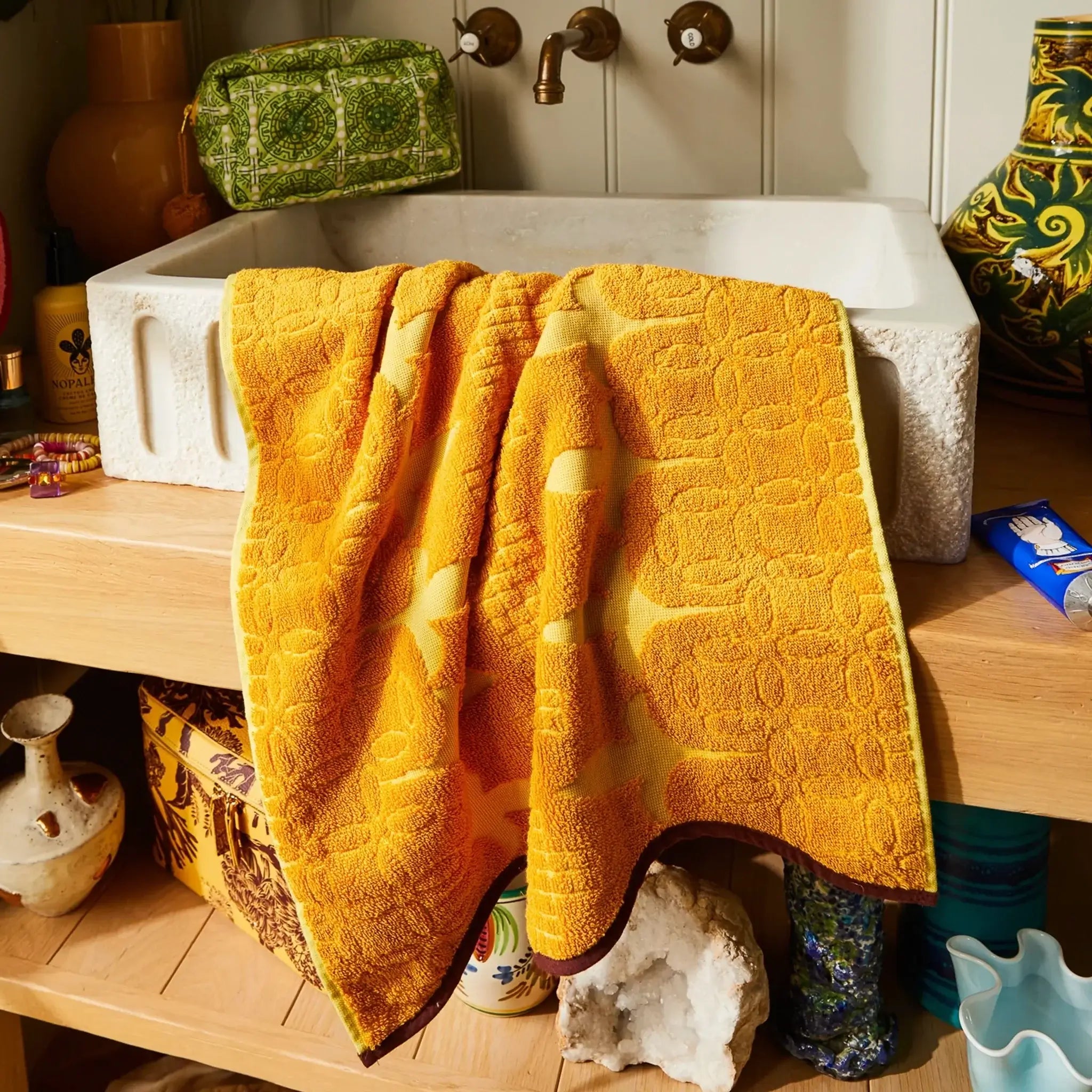 Yellow textured towel draped over a sink in a bathroom setting with various items around.