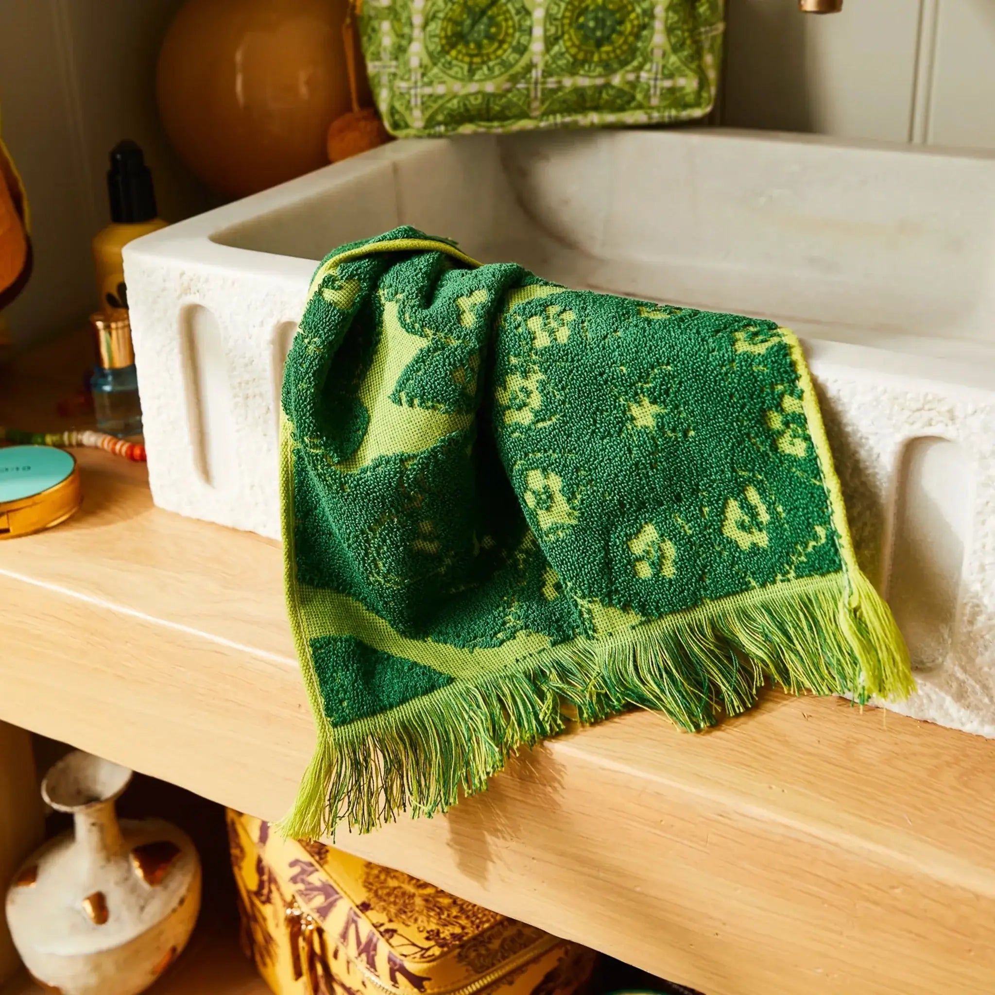 Green patterned wash cloth draped over a white sink in a bathroom setting.
