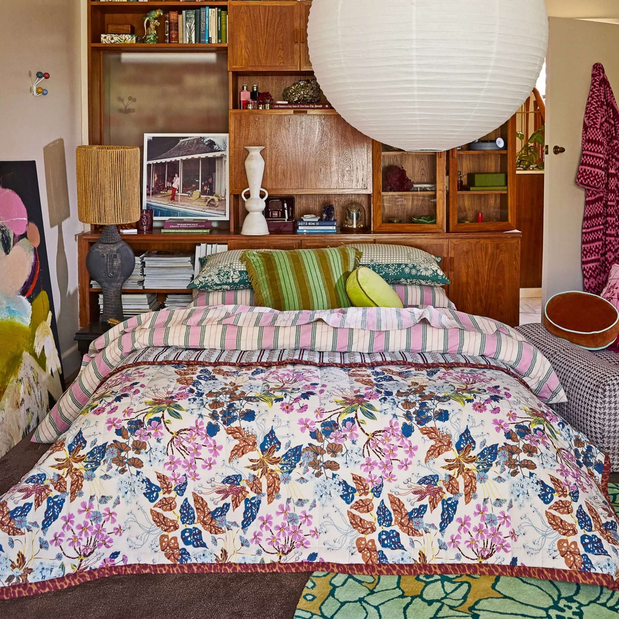 A multicolored floral blanket with a mix of animal patterns, featuring a combination of flowers and geometric shapes in a mix of beige, white, and dark colors on a bed.