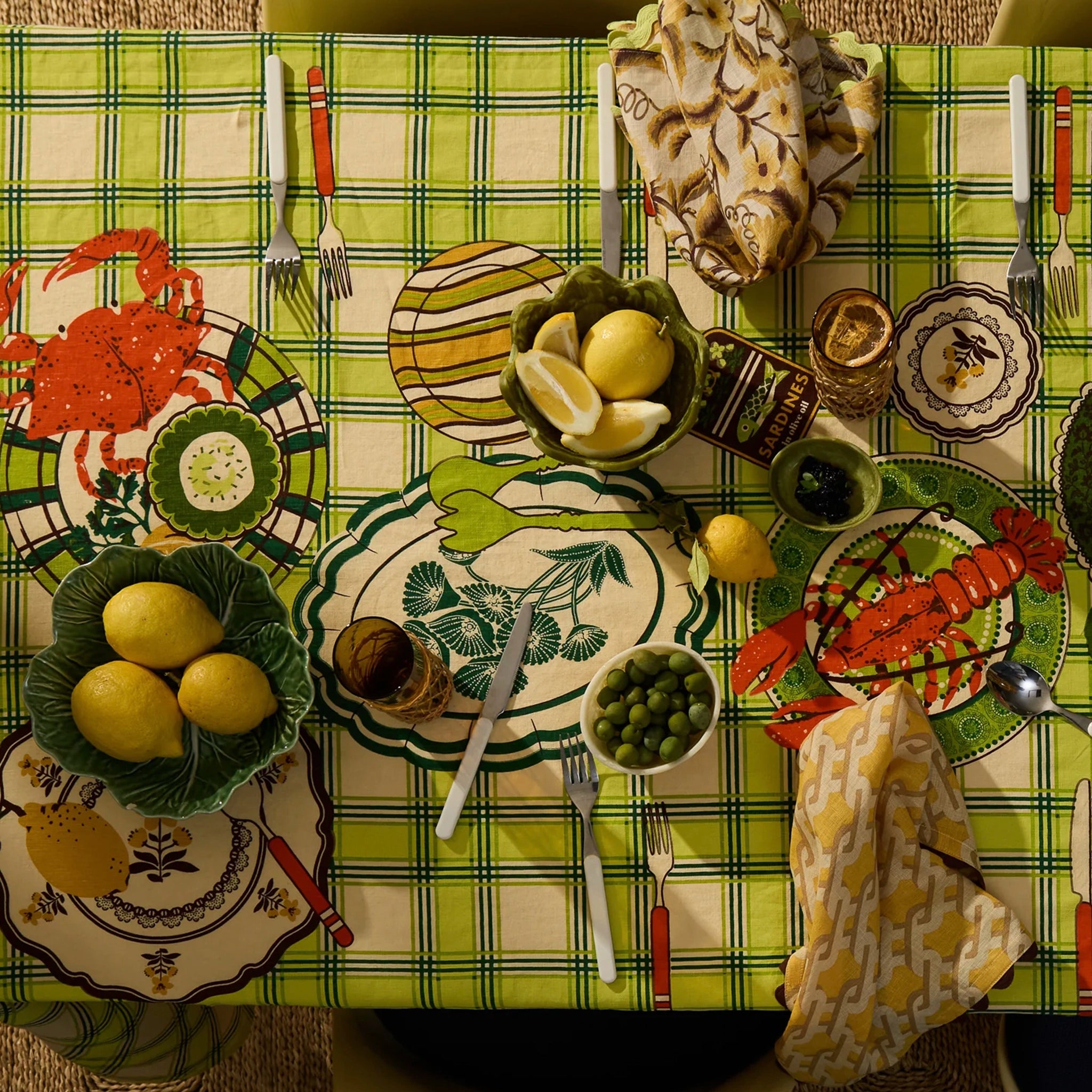 Dining table set with seafood-themed plates, lemons, and a checkered tablecloth.
