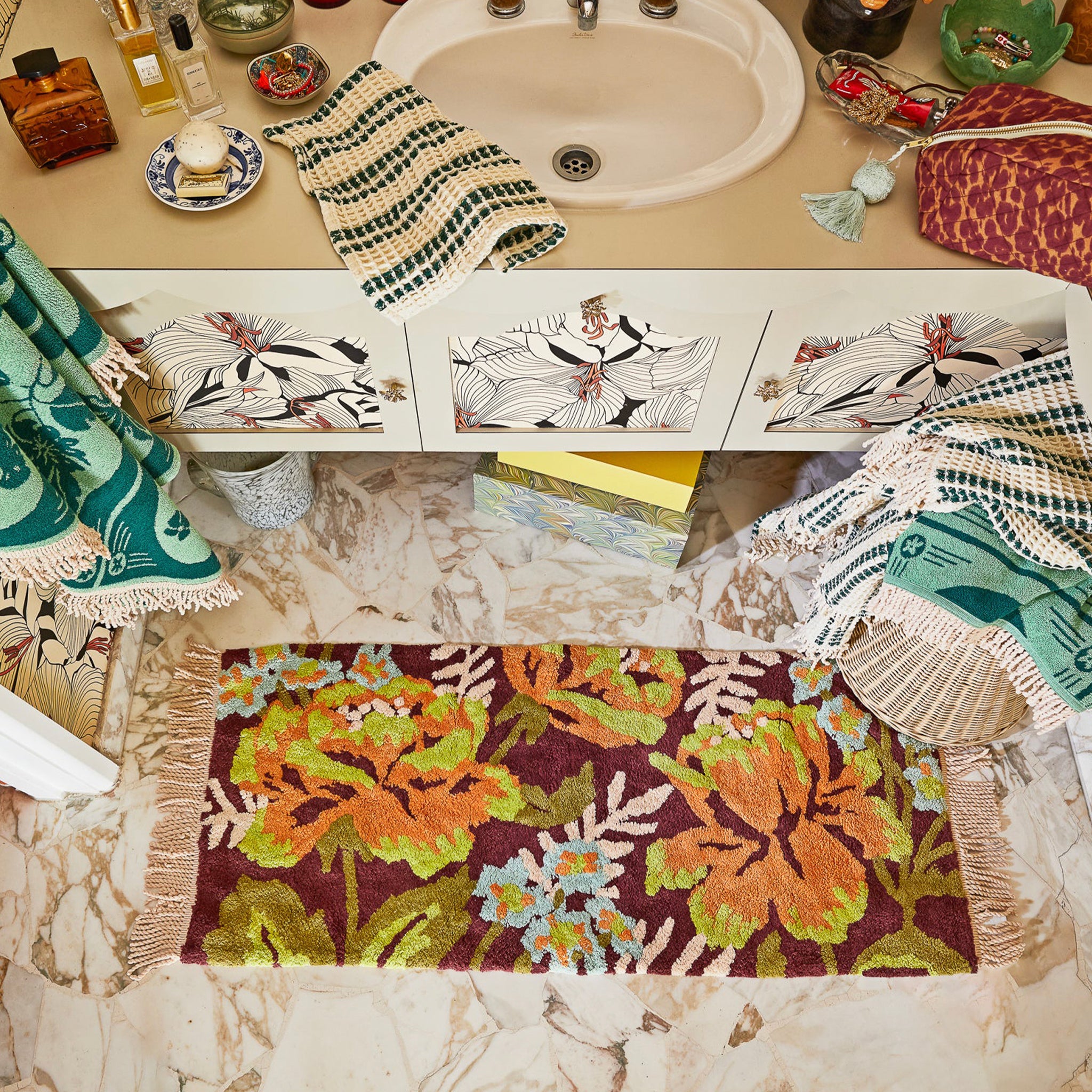 Bathroom with floral bath mat, towels, and decorative items on a counter.