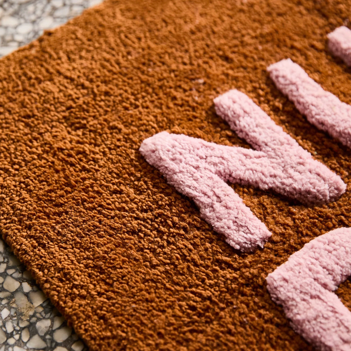 Sage x Clare Nudie Bath Mat Mini - Russet close-up of pink tufted lettering on russet terry