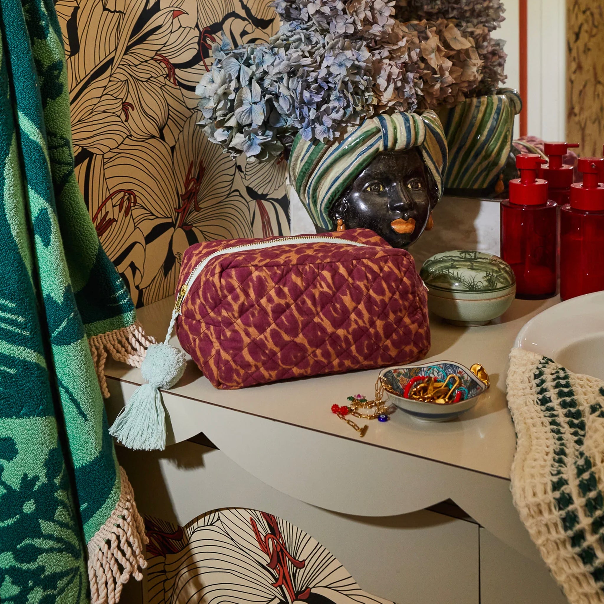 Leopard print pouch on a table with decorative items and patterned wall in the background