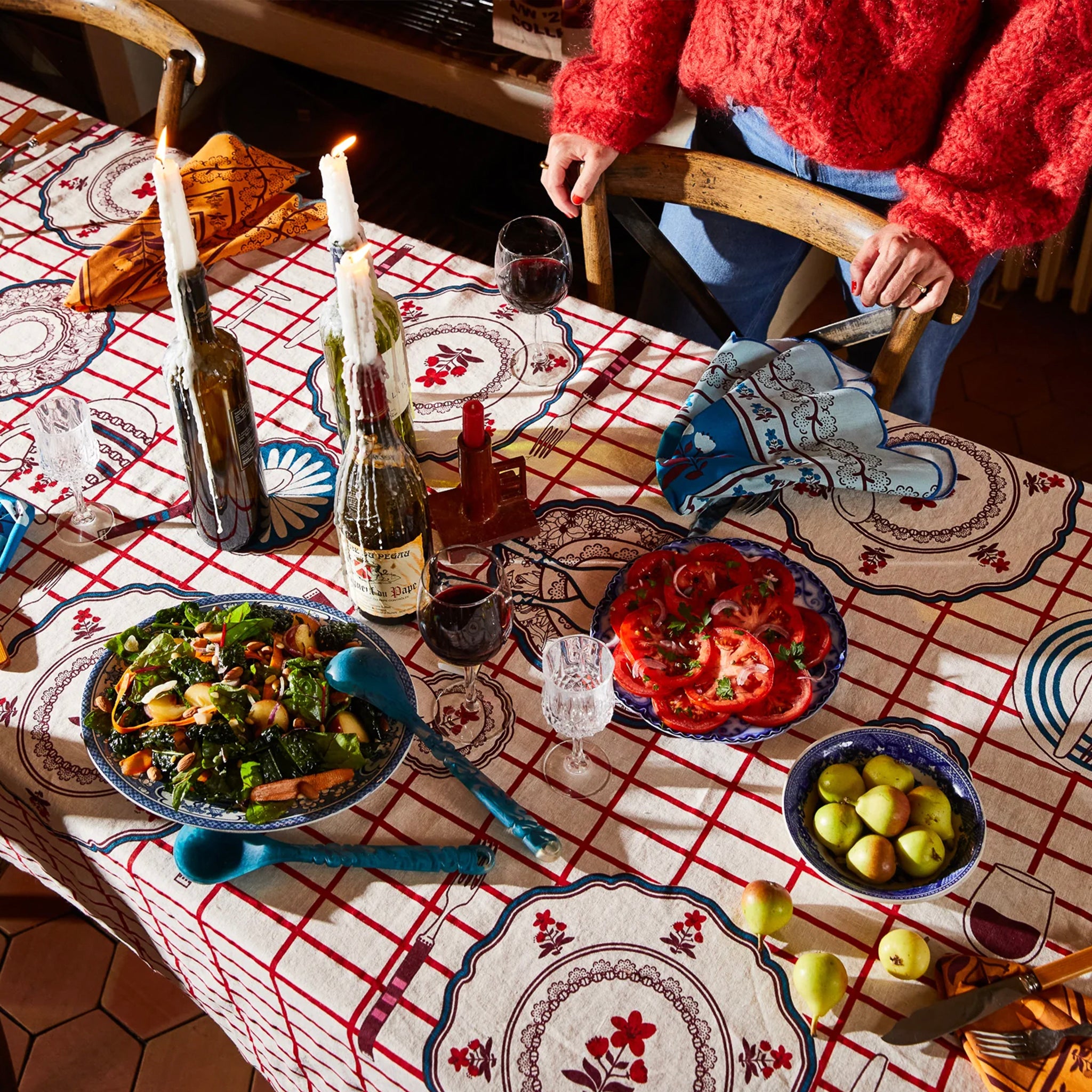 A red and white checkered tablecloth with floral and geometric patterns in the center set on a table.