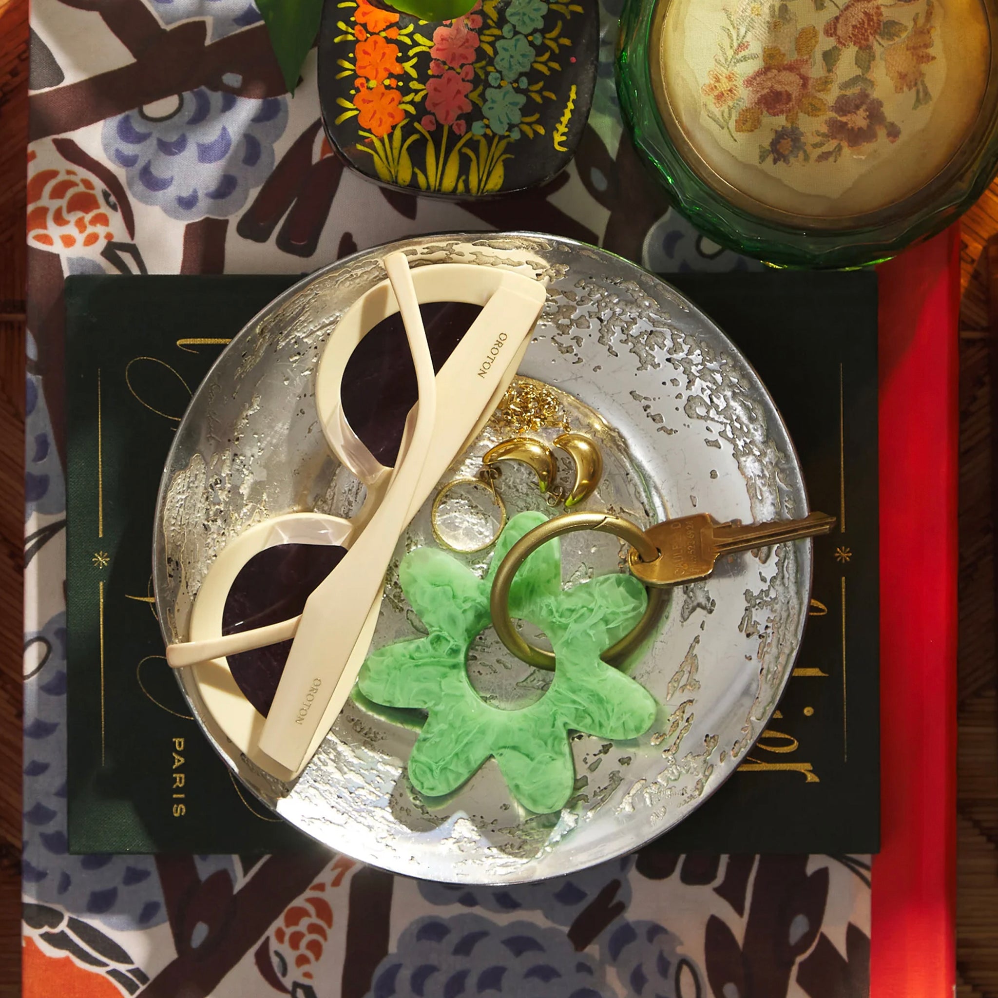 A green resin keyring in a flower shape with gold-toned hardware.