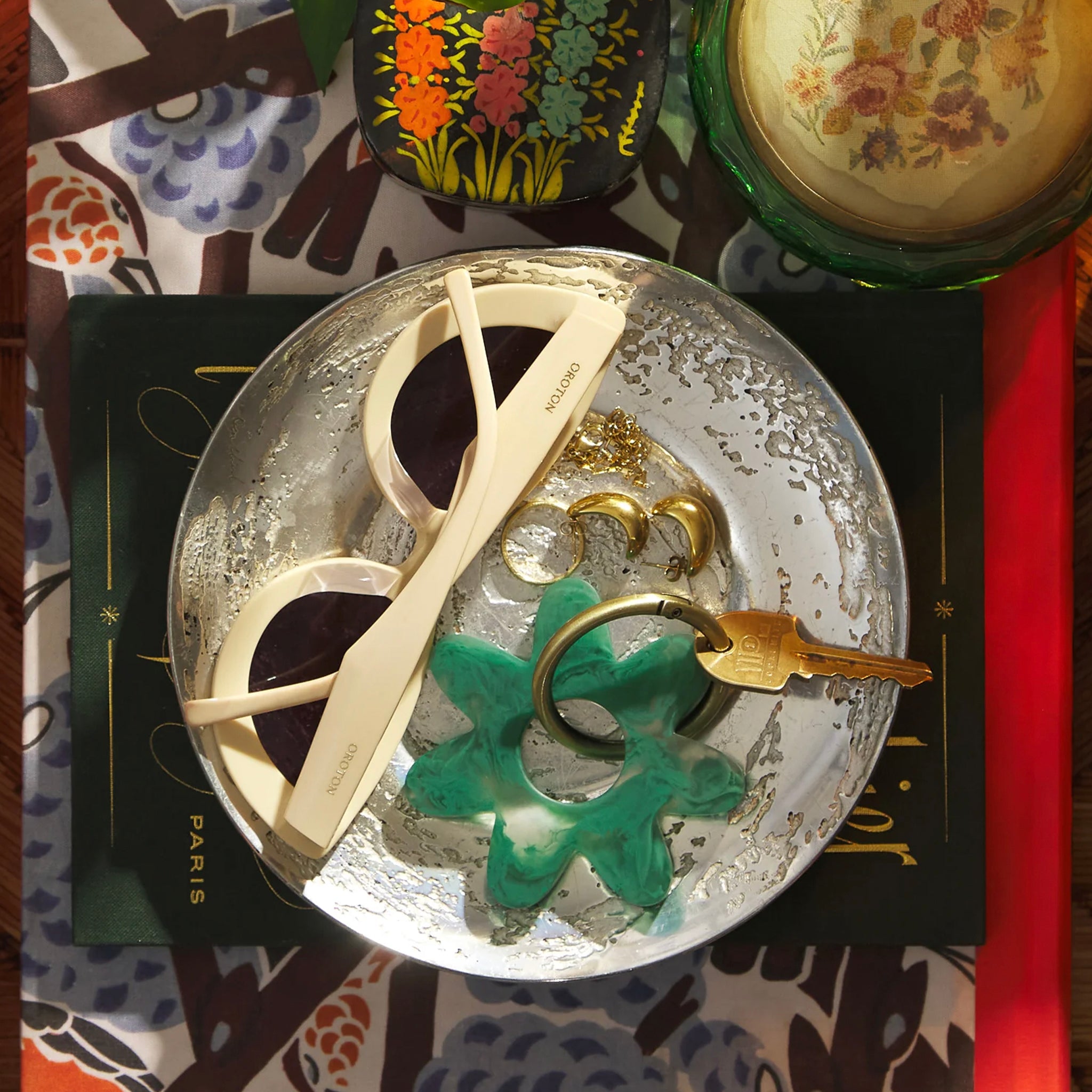 A green resin keyring in a flower shape with gold-toned hardware.