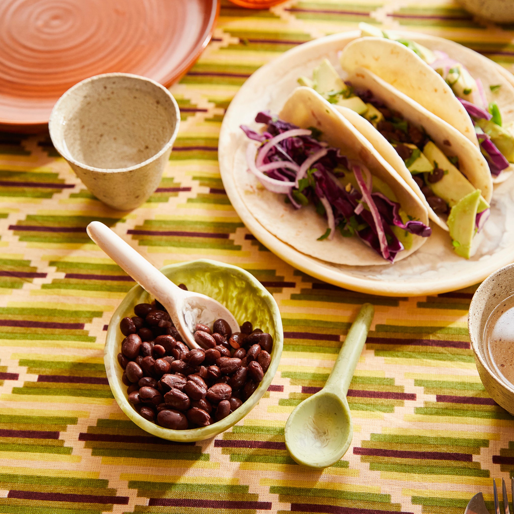 A single green resin spoon with a smooth finish and a handle on a table.