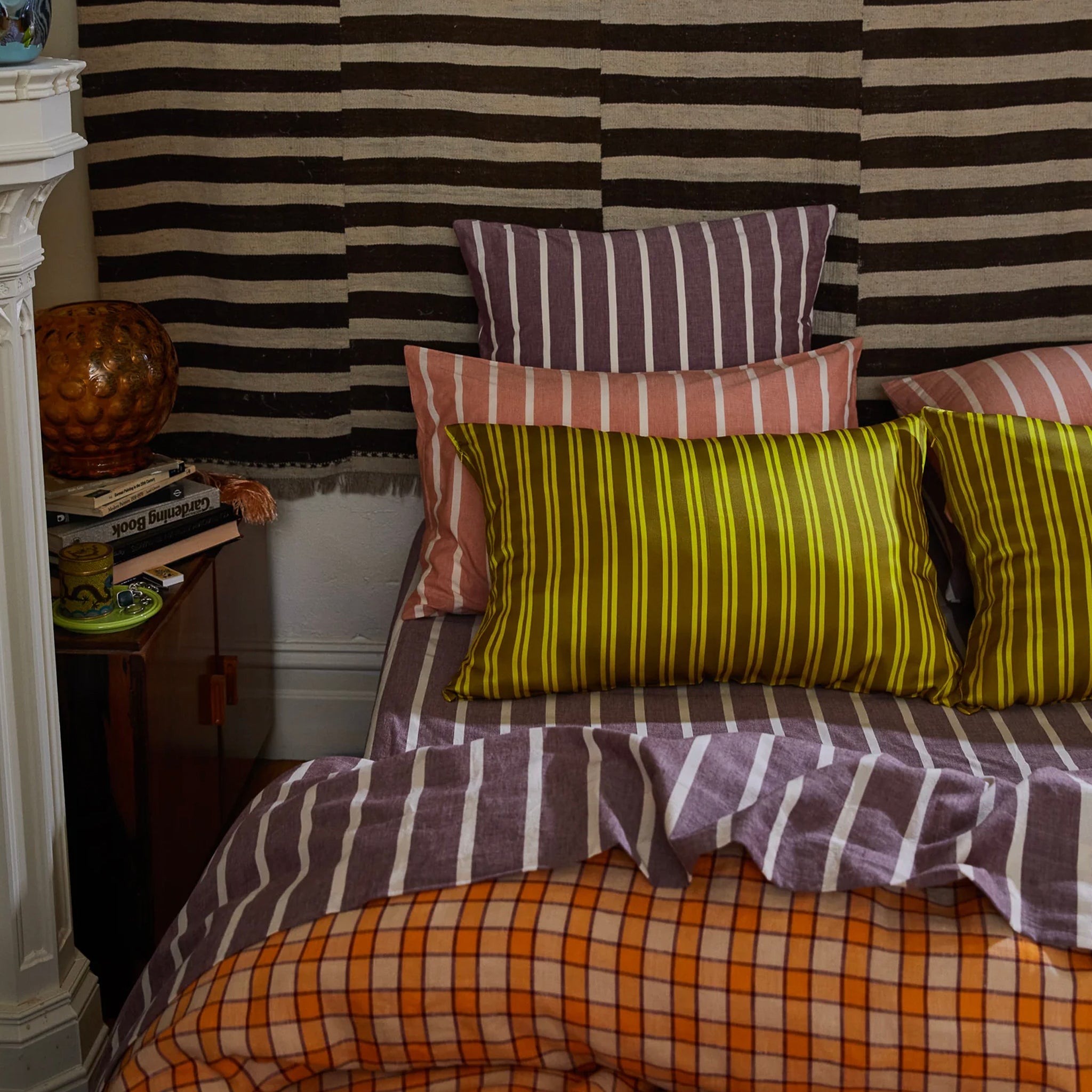 Bed with striped bedding and pillows against a striped wall.