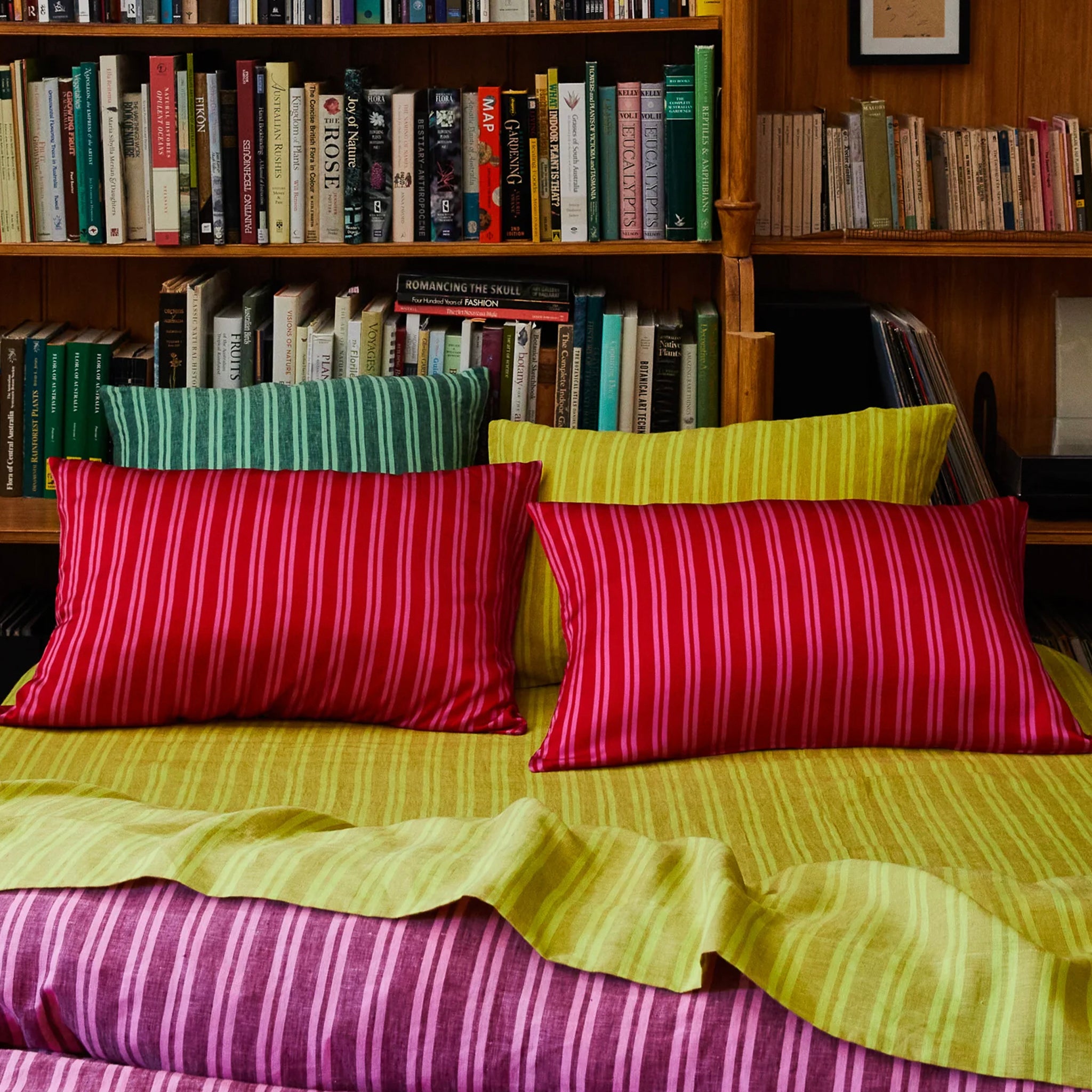 Striped pillows on a bed with bookshelves in the background