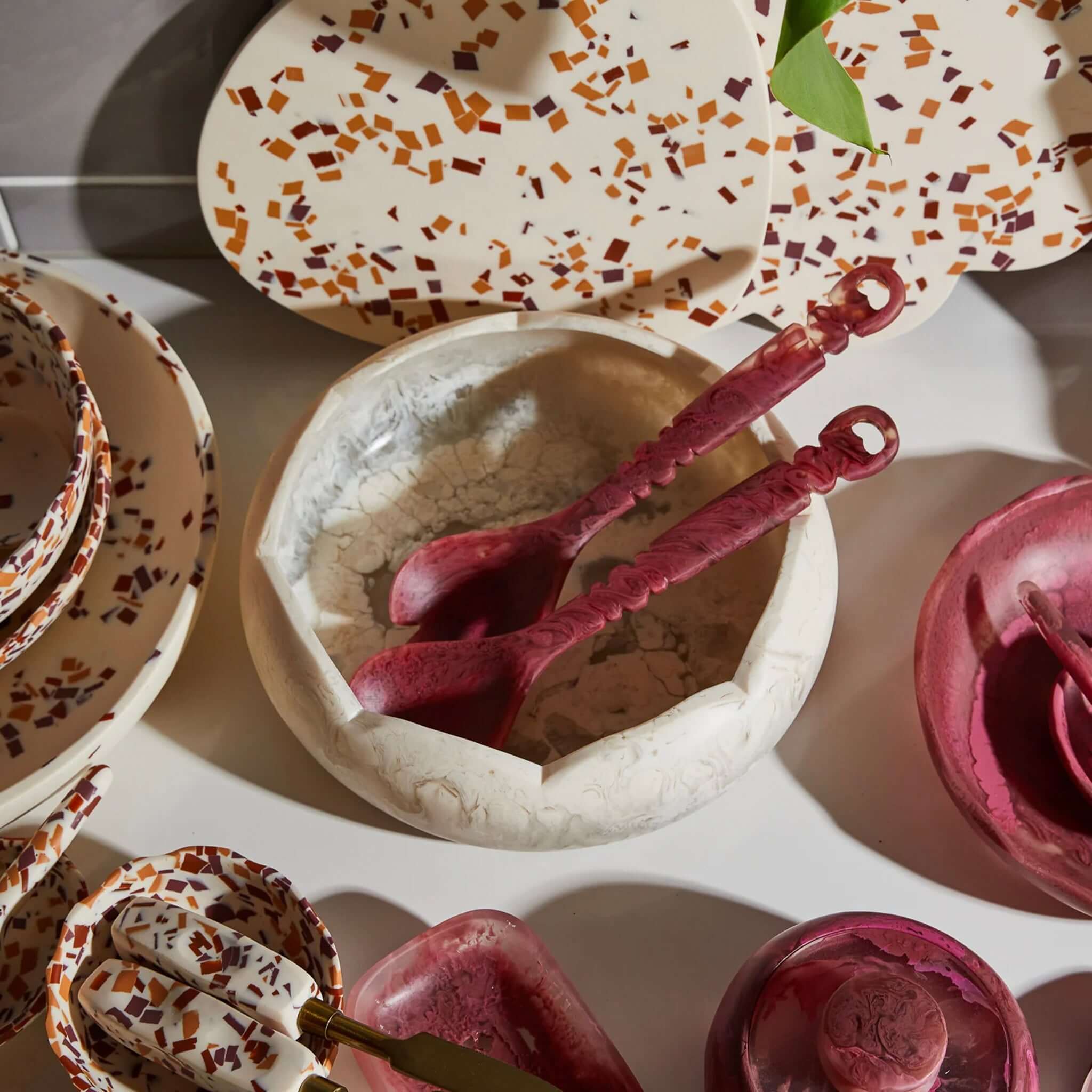 Alt Tag: Sage x Clare Resin Kabrina Bowl - Crema hand-swirled scalloped resin bowl styled with serving spoons and terrazzo tableware