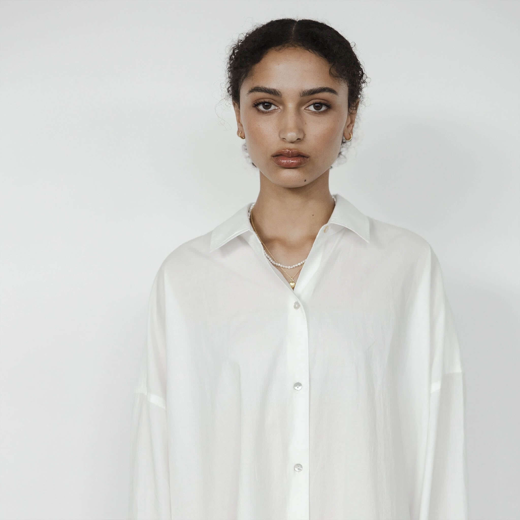 Alt Tag: Sophie Always Shirt - White oversized white cotton button-up with shell buttons and curved hemline, worn by model