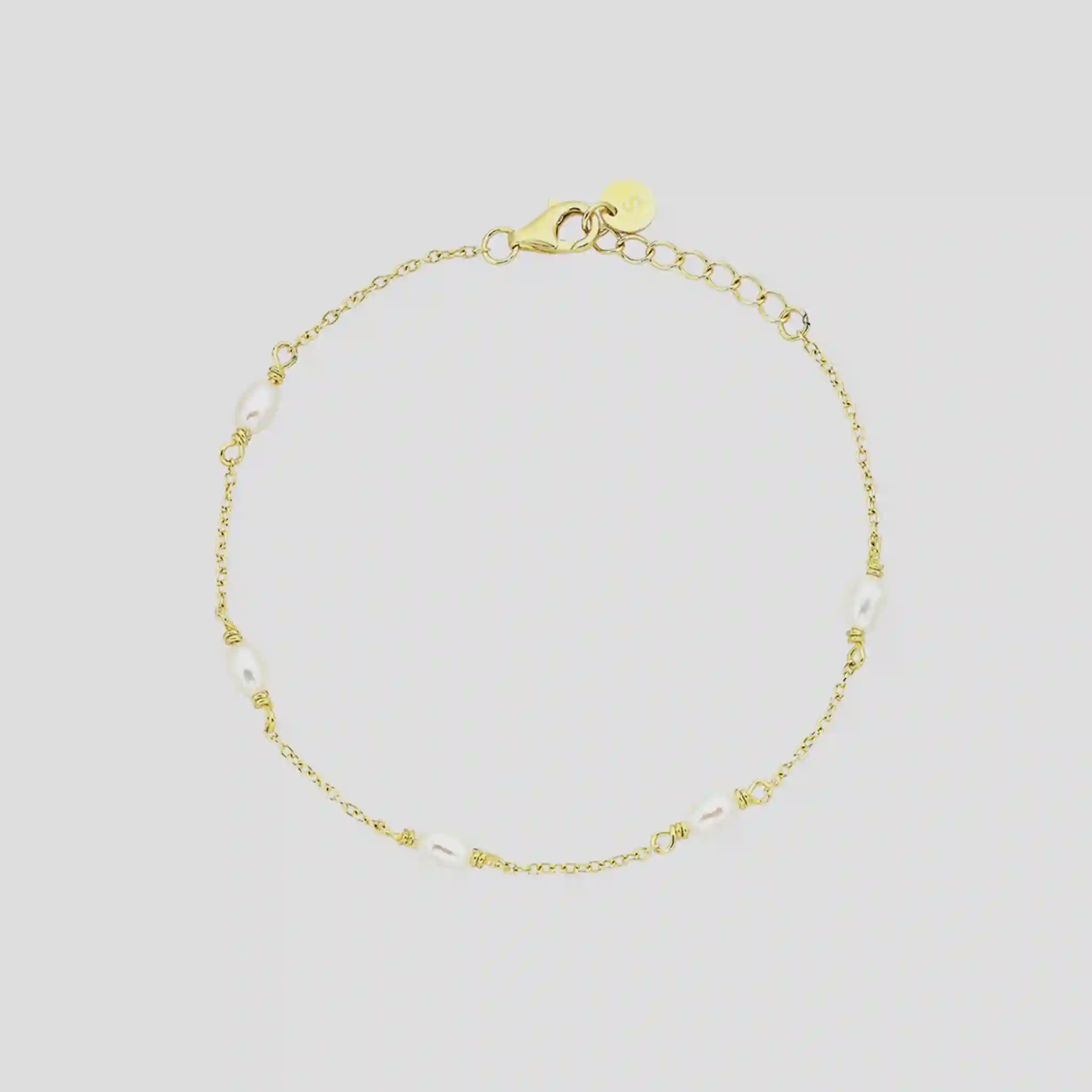 Gold bracelet with small beads on a light gray background