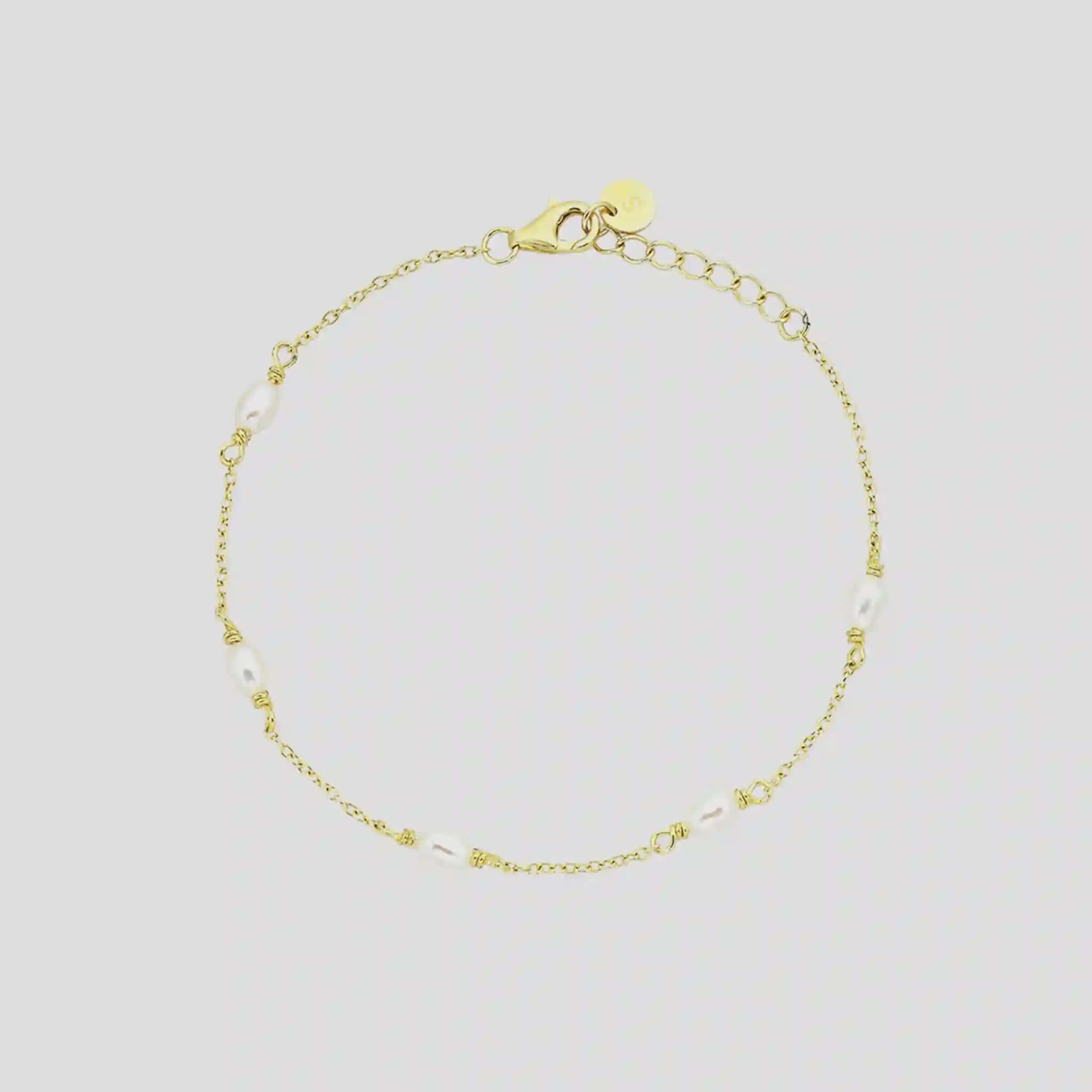 Gold bracelet with small beads on a light gray background