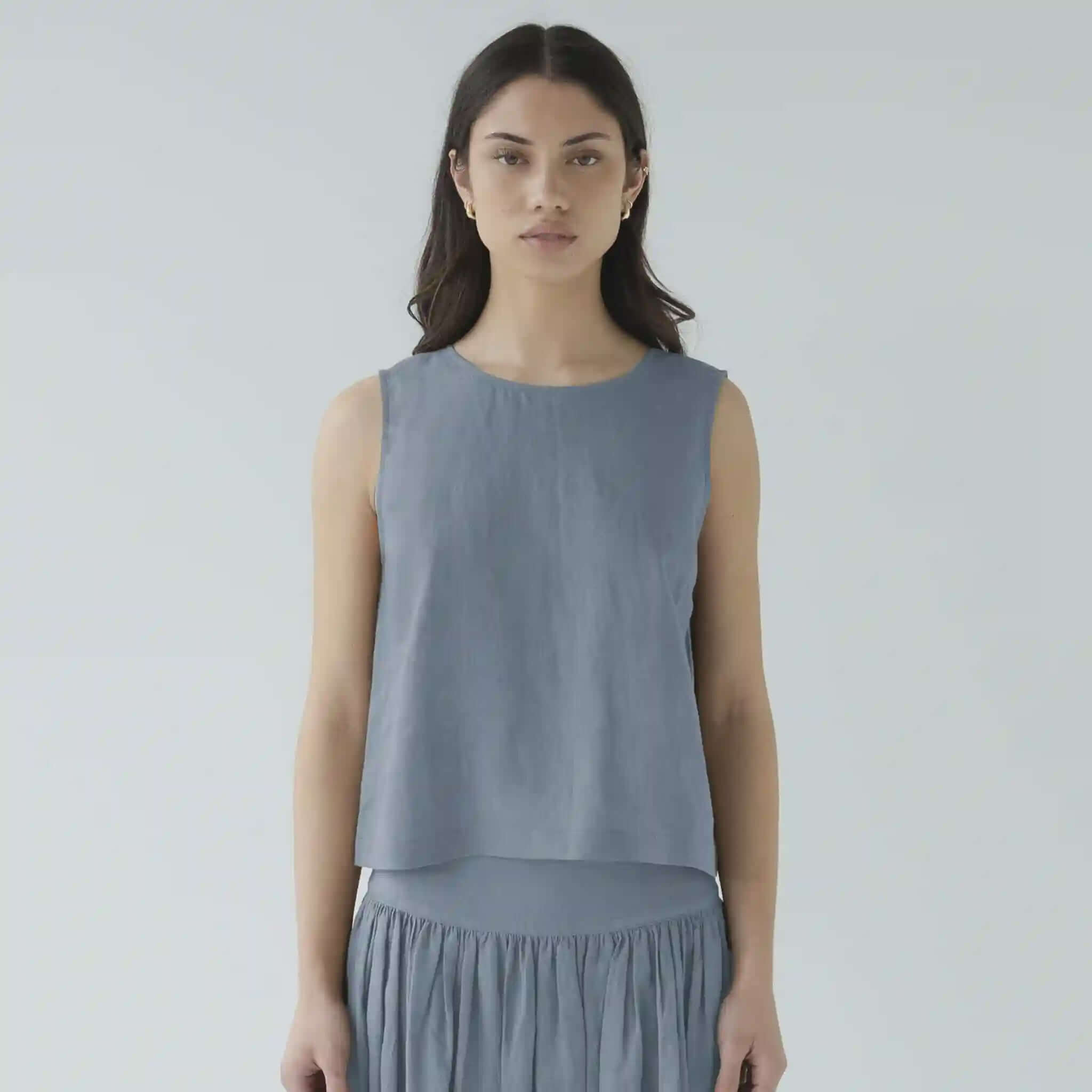 Woman wearing a sleeveless gray top and skirt against a plain background