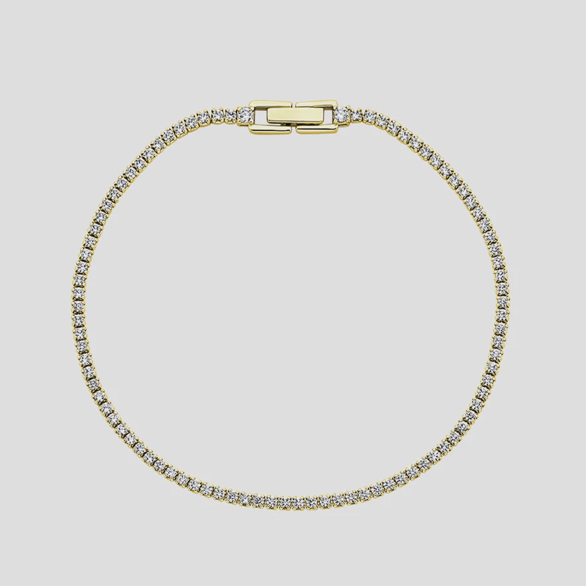 Gold bracelet with clear stones on a light gray background