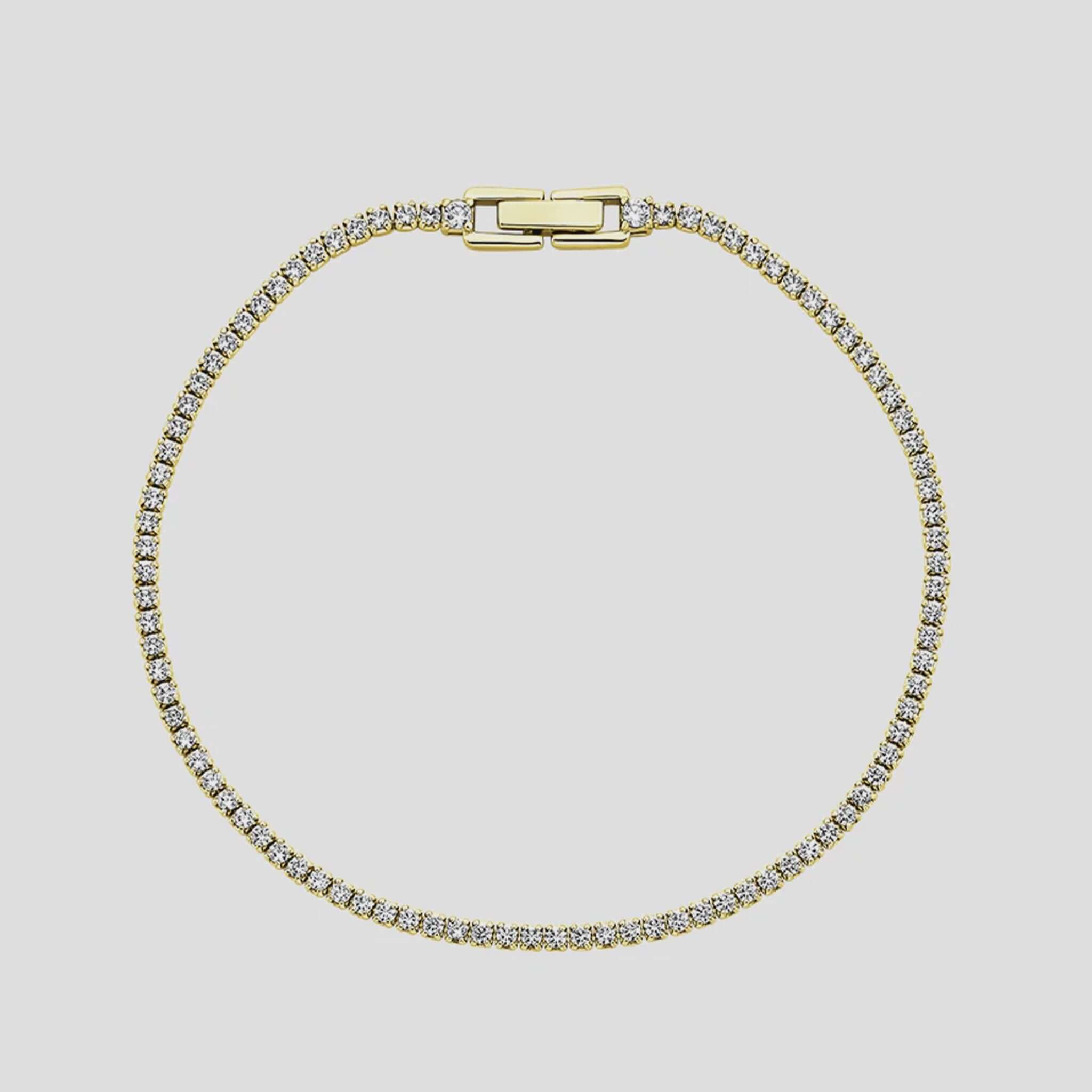 Gold bracelet with clear stones on a light gray background
