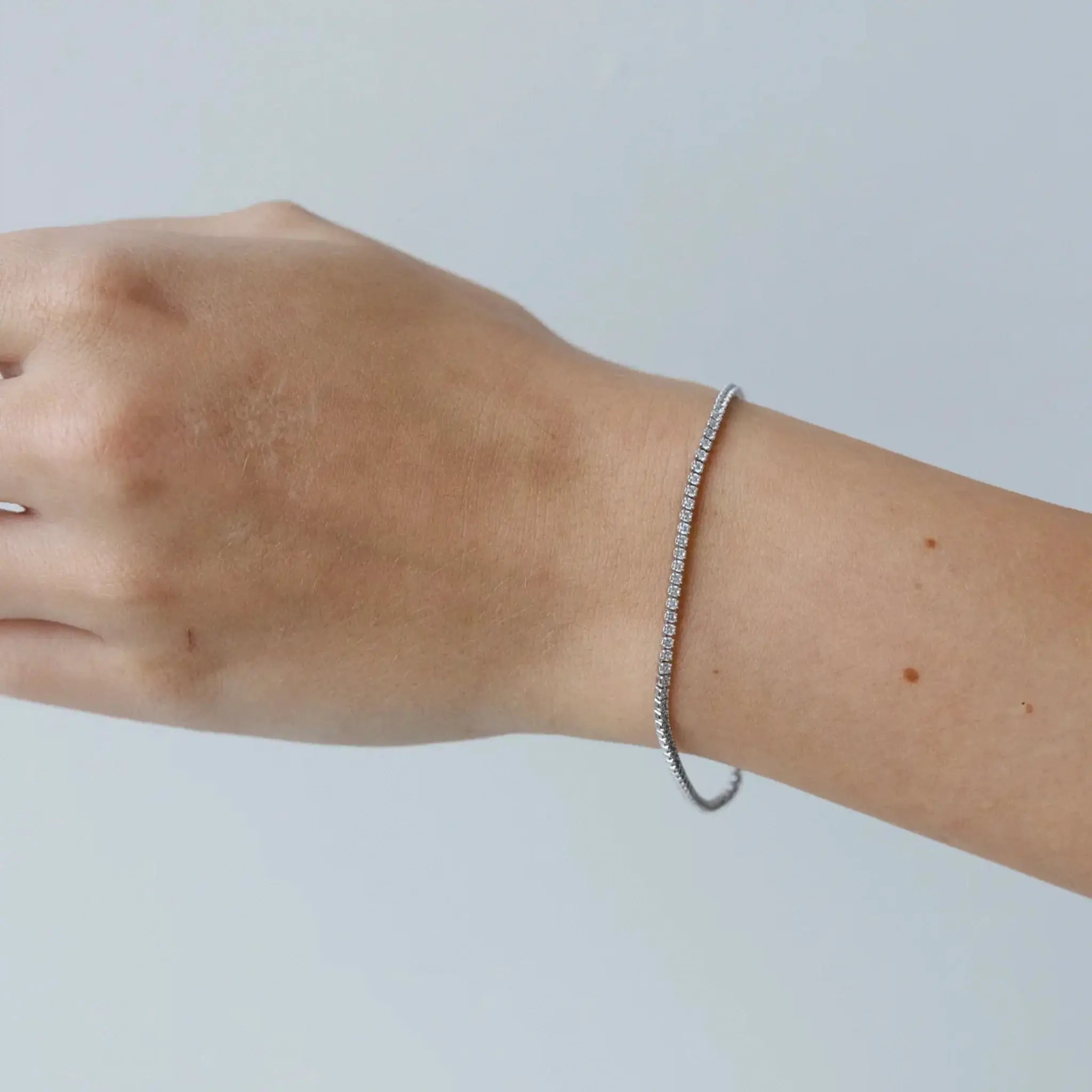 Silver bracelet on a wrist against a plain background