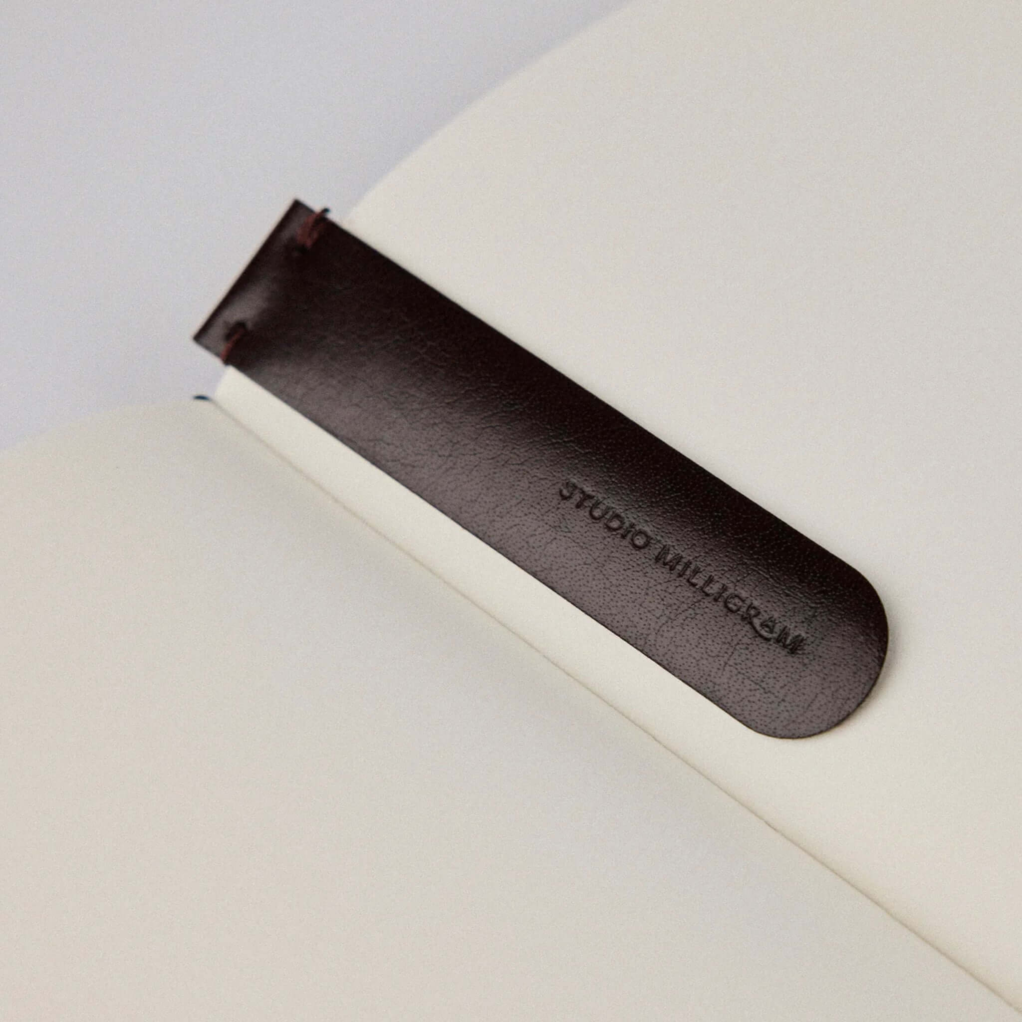 Studio Milligram Recycled Leather Bookmark - Burgundy elegantly placed inside a book, showcasing its sleek design.