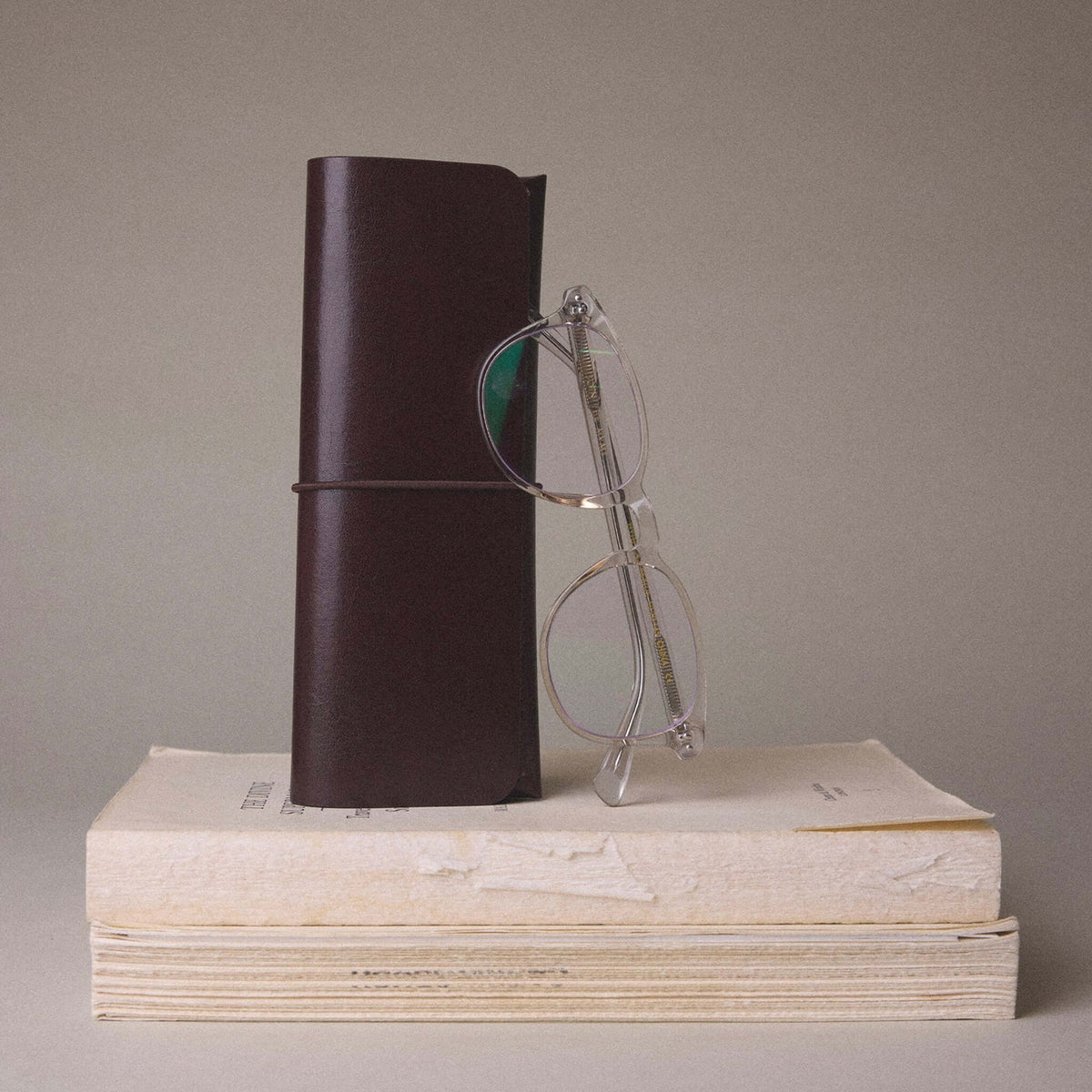 Milligram Recycled Leather Pen Case - Chocolate with glasses on vintage books background.
