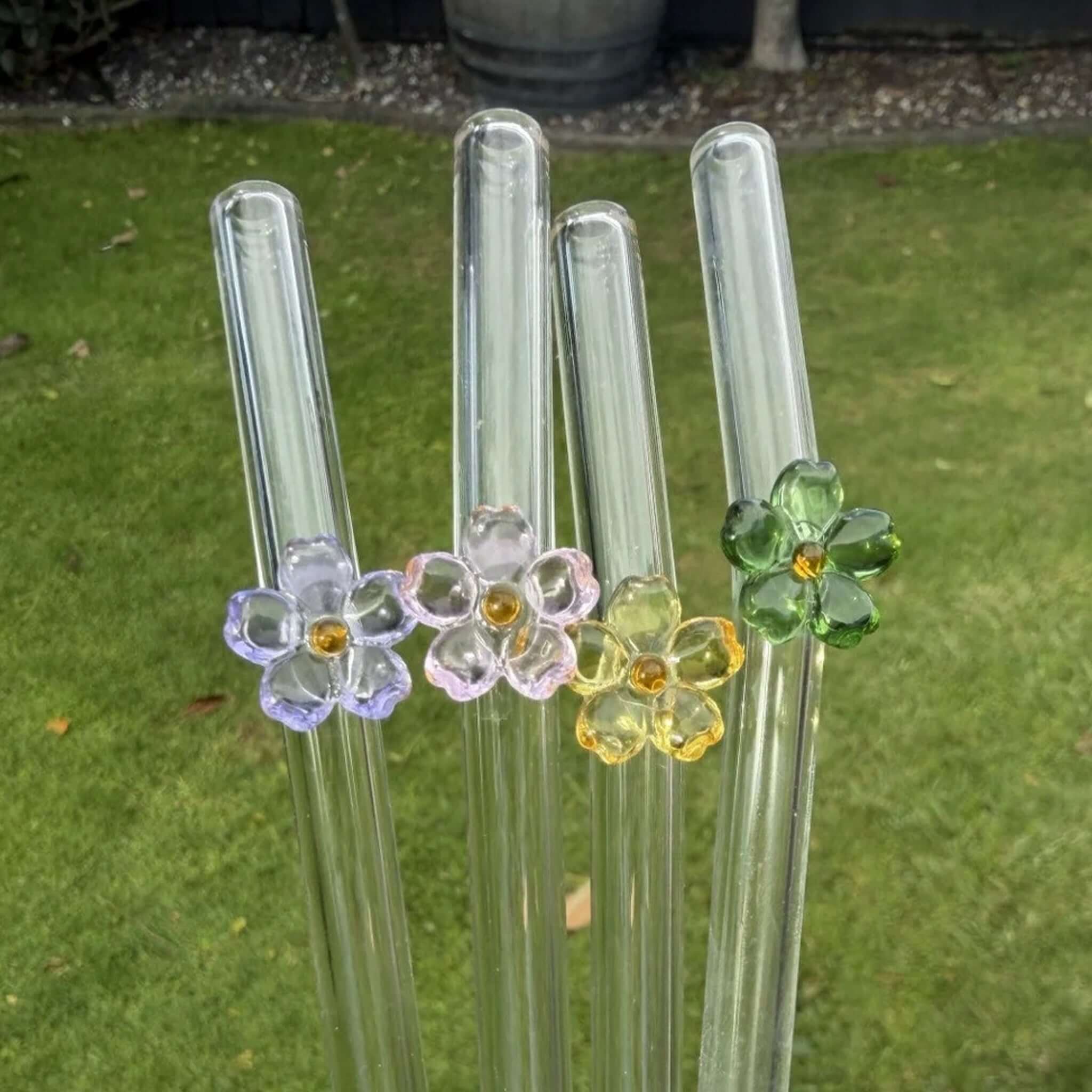 Sucker Glass Wildflower Drinking Straw Set featuring four glass straws with flower charms in lavender, pink, green, and amber.