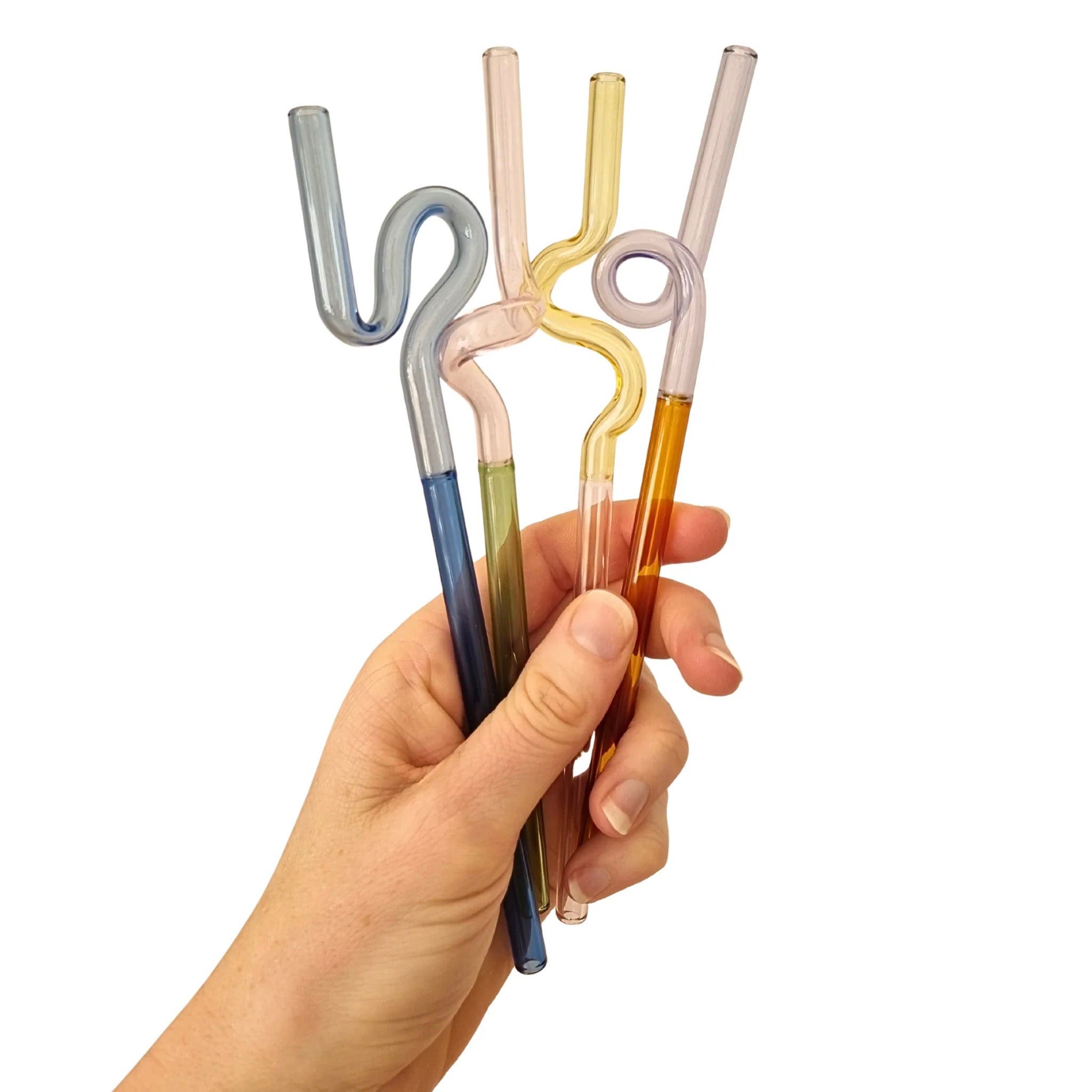 Hand holding four colorful glass straws against a white background