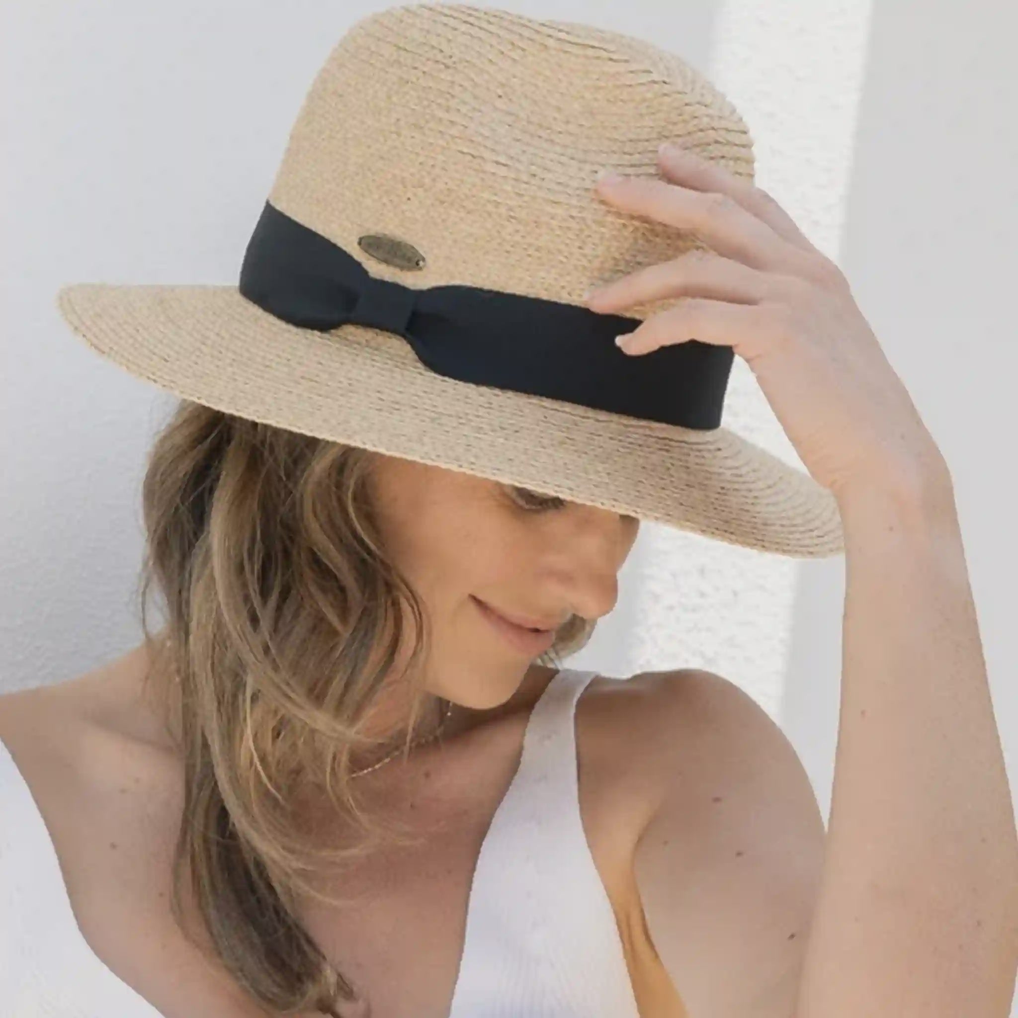 Woman wearing a straw hat with a black ribbon on a white background