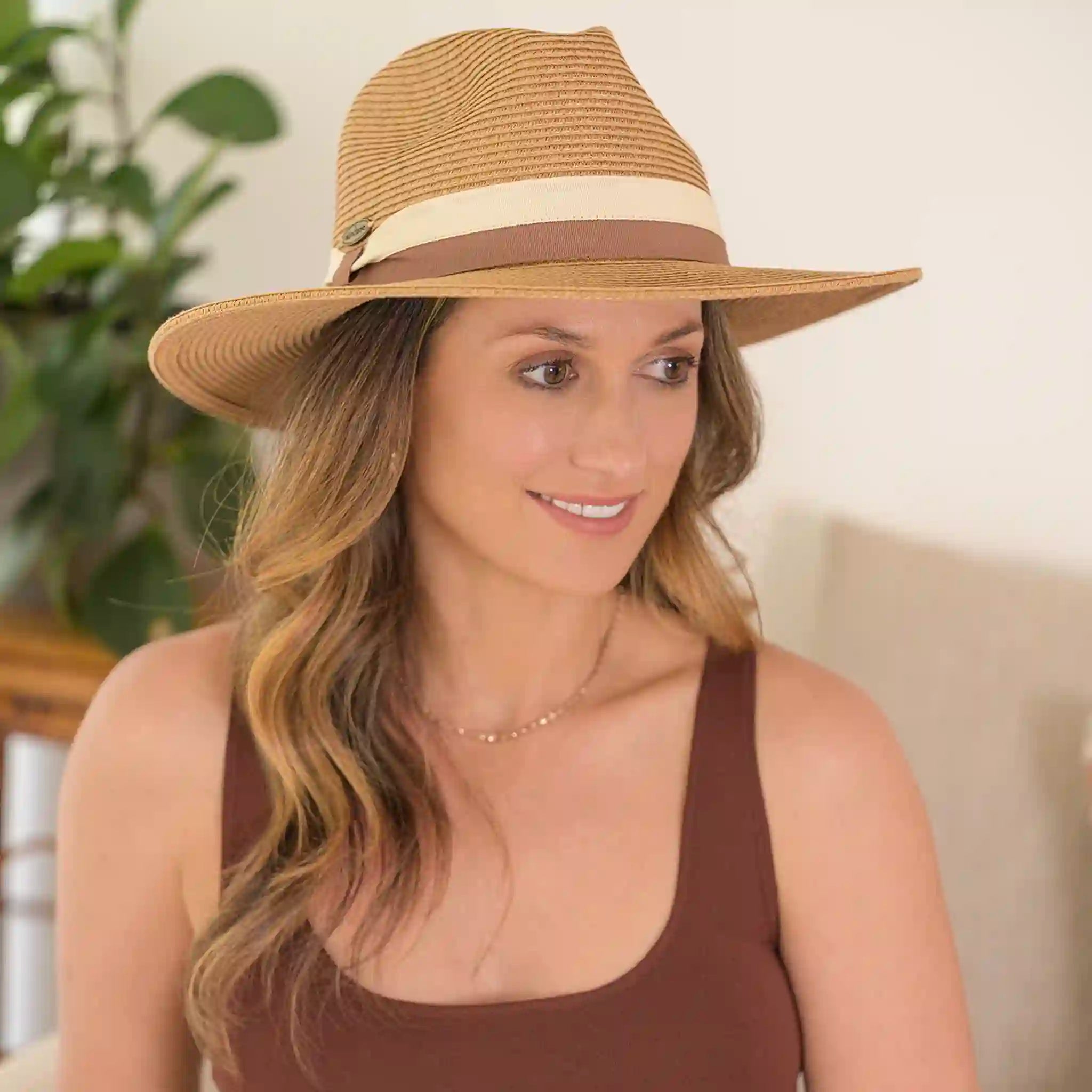 Woman wearing a brown straw hat with a beige band indoors