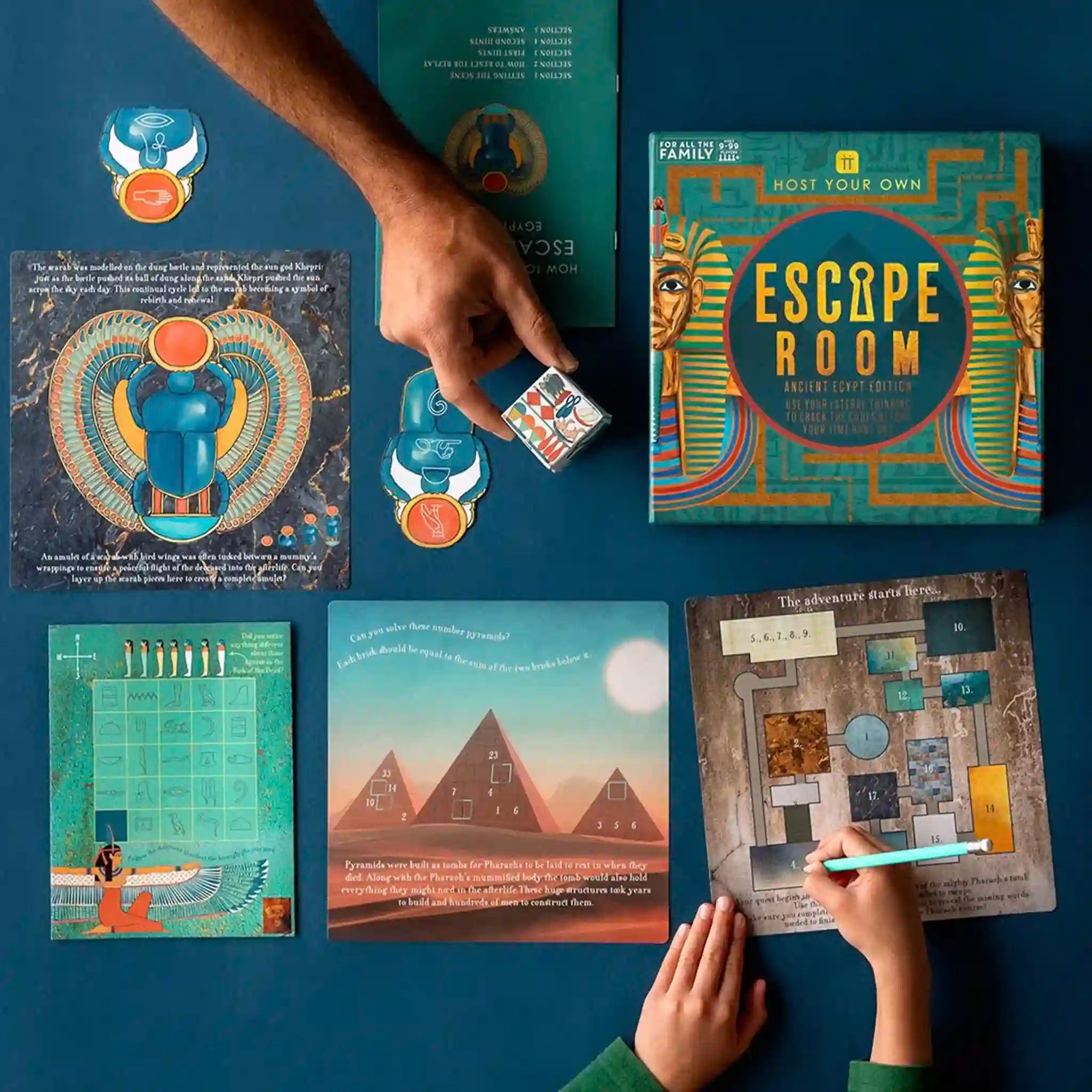 Escape room game components on a blue surface with hands interacting.