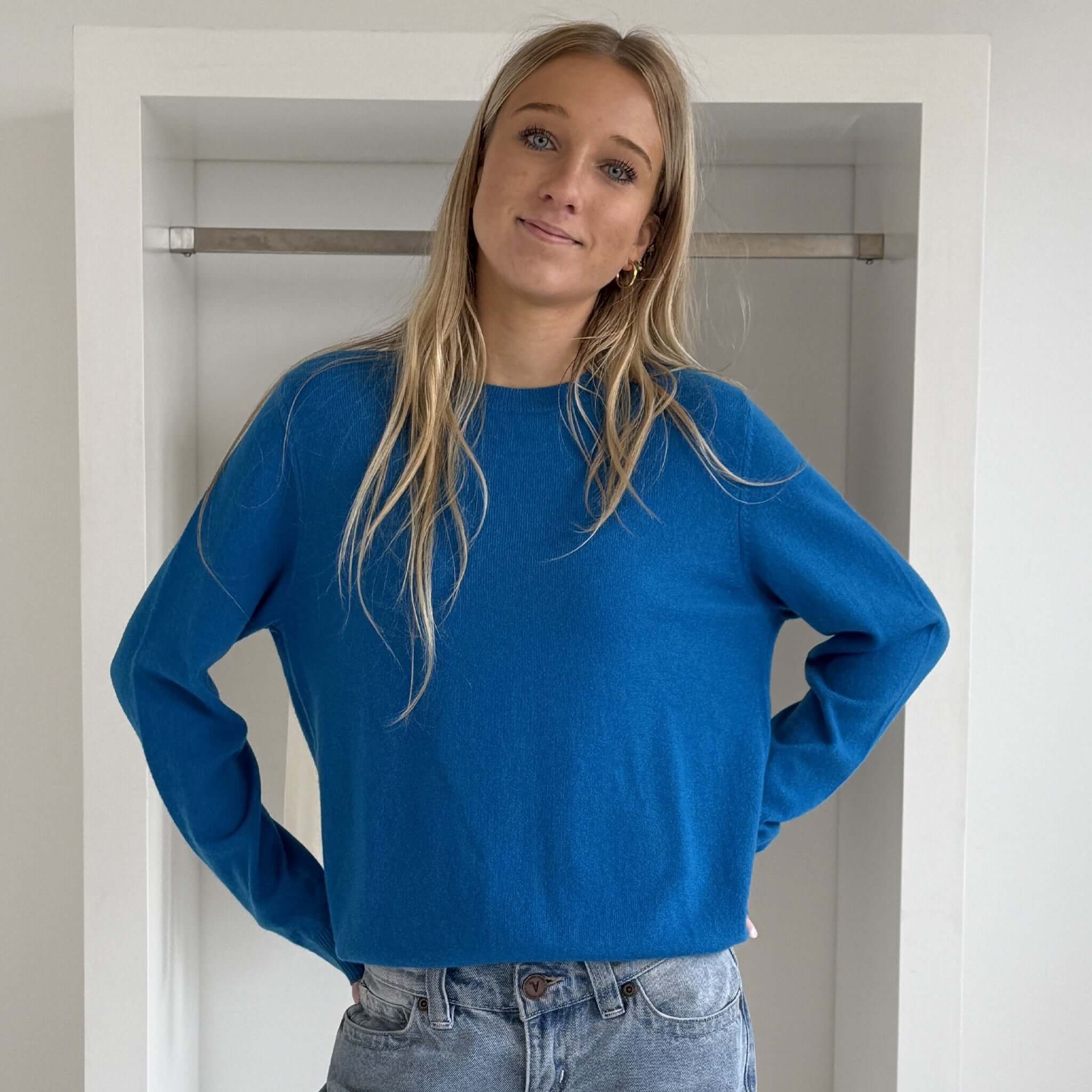 The Uniform Cashmere Crew Neck Sweater - Sapphire worn by a model, showcasing its relaxed fit and vibrant sapphire color.