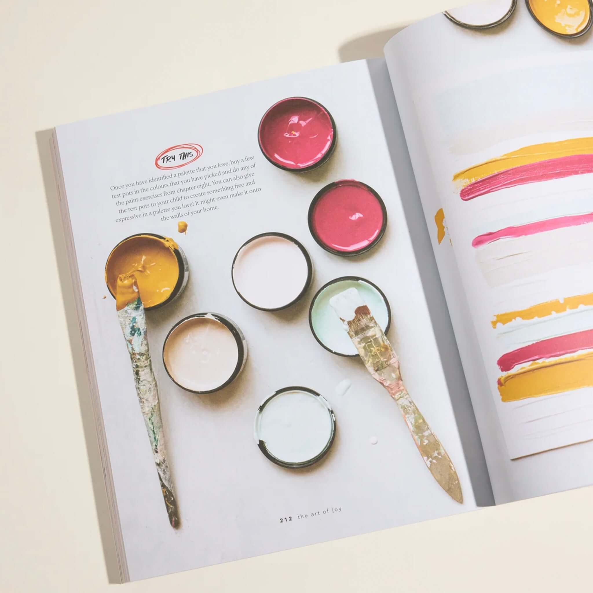 The Art of Joy: Easy Daily Rituals and Practices for a Wonder Filled Life open book with paint pots, brushes, and colourful swatches