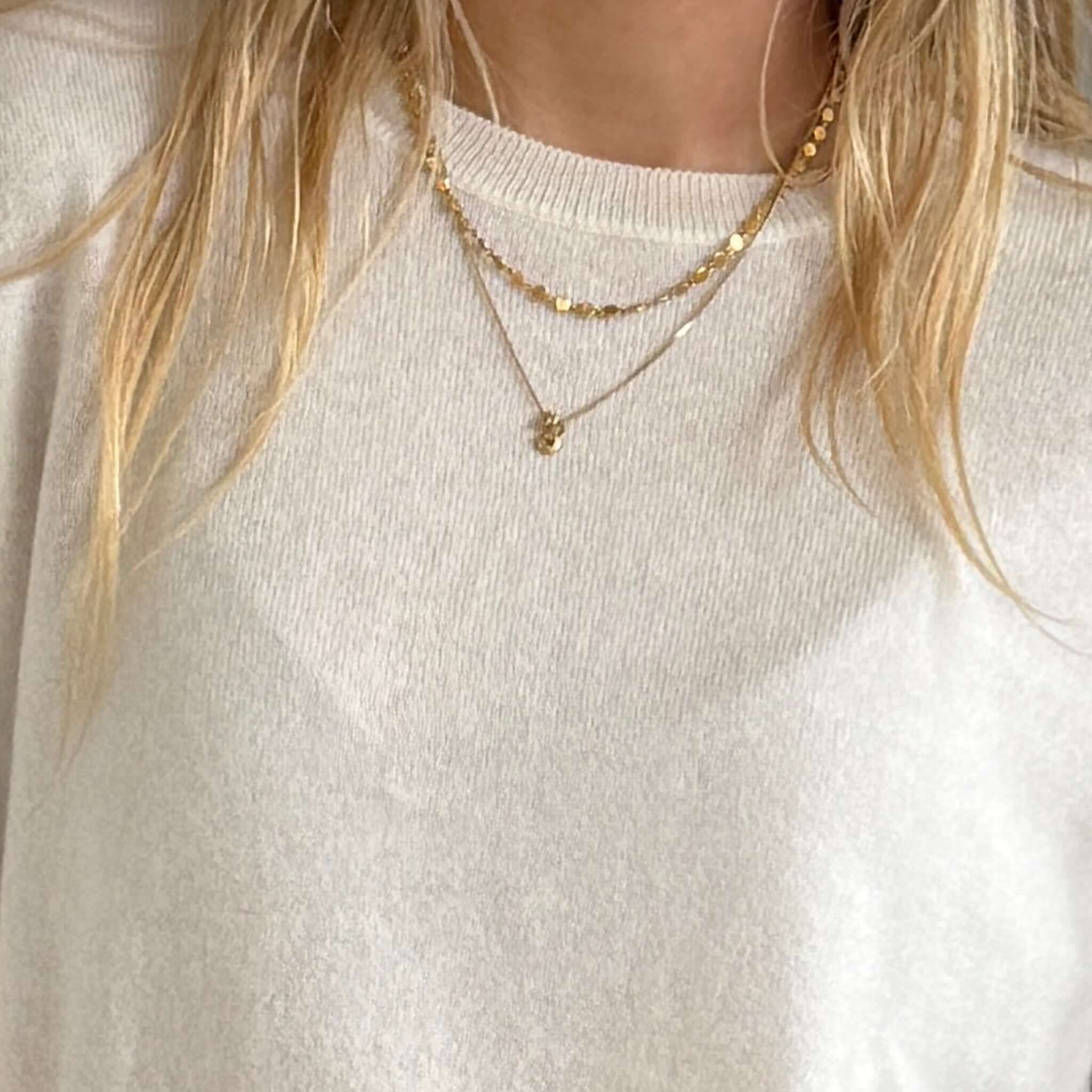 The Uniform Cashmere Crew Neck Sweater - Milk worn with layered gold necklaces for a chic look.