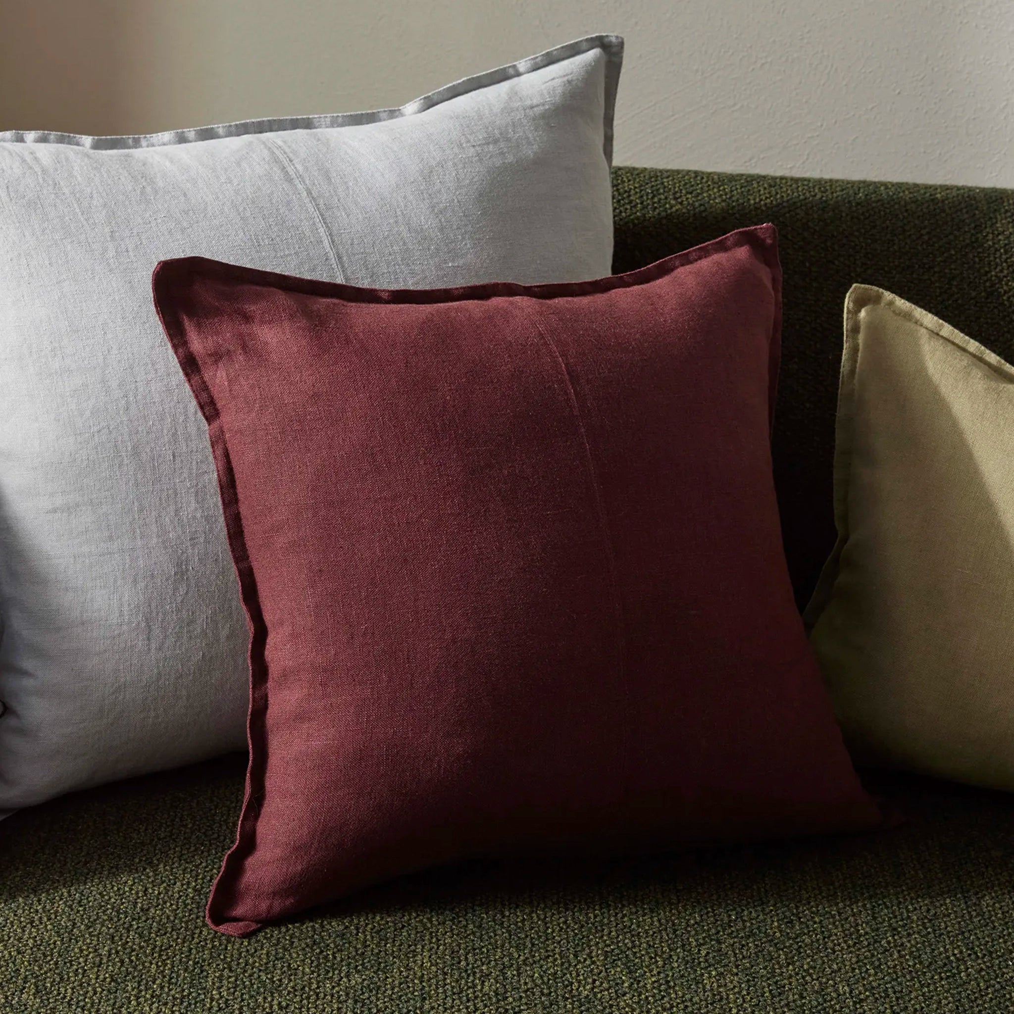 Three pillows in different colors on a sofa.